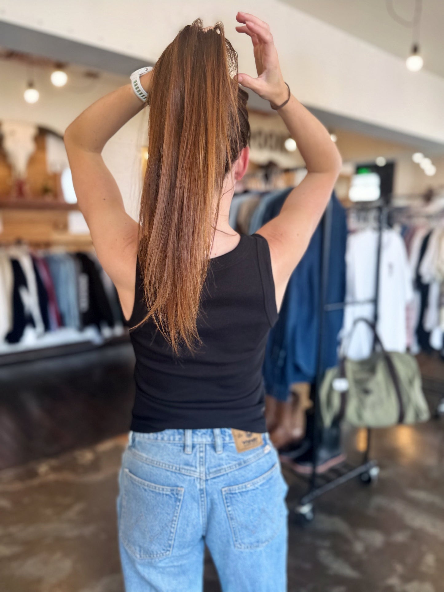 Person in a clothing store adjusting hair with clothes in the background