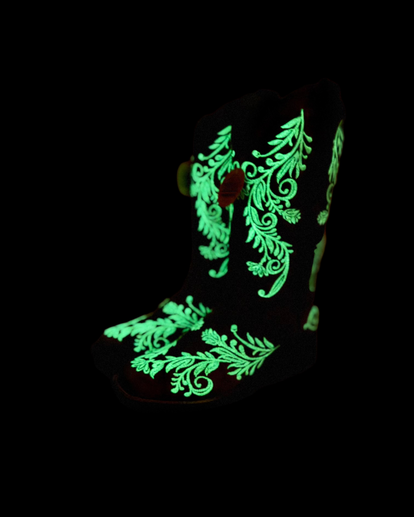 A pair of Corral cowboy boots with intricate white embroidery on distressed brown leather. The boots feature a classic western silhouette with a pointed toe, sturdy black heel, and a turquoise interior lining. The detailed floral embroidery not only adds an elegant touch but also features glow-in-the-dark white stitching, making these boots stand out both day and night.