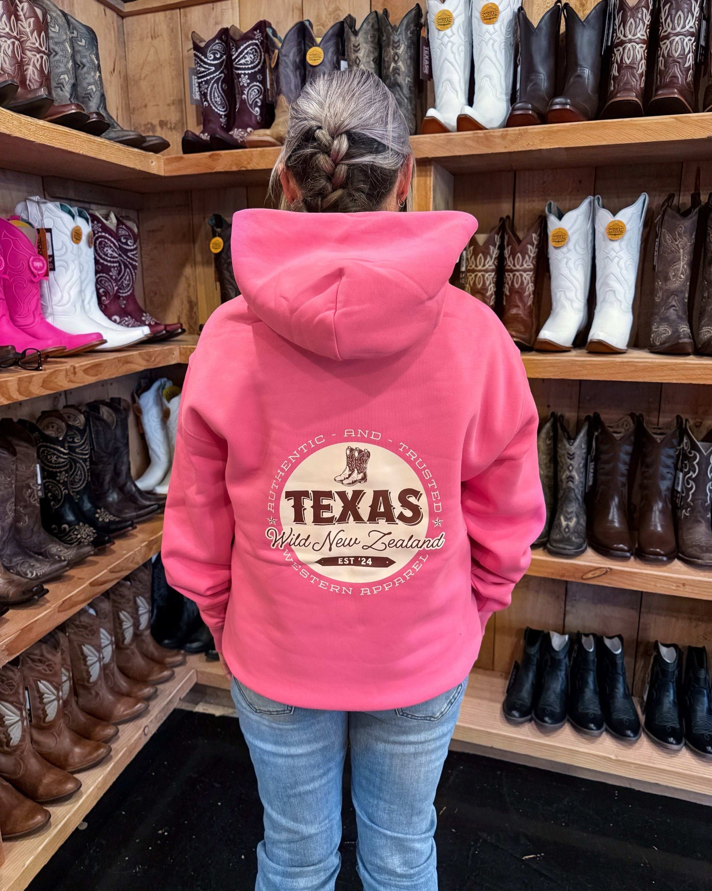 Hot pink Texas Western Apparel hoodie with intricate embroidery. The front features a detailed embroidered 'T' and a Western-style boot, while the back showcases the Texas Western Apparel logo. A bold and stylish statement piece with a classic country flair.