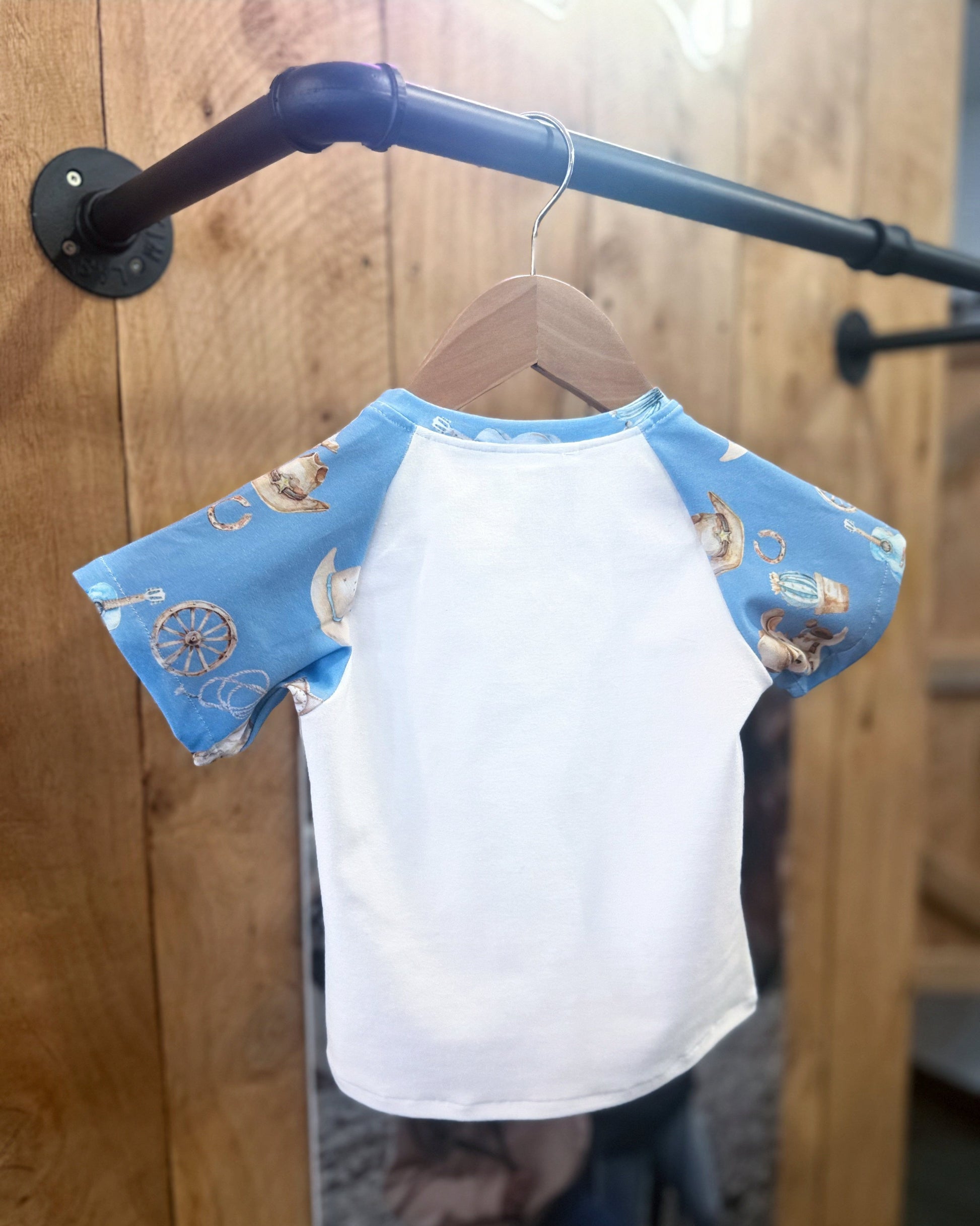 White shirt with blue sleeves on a hanger against a wooden background