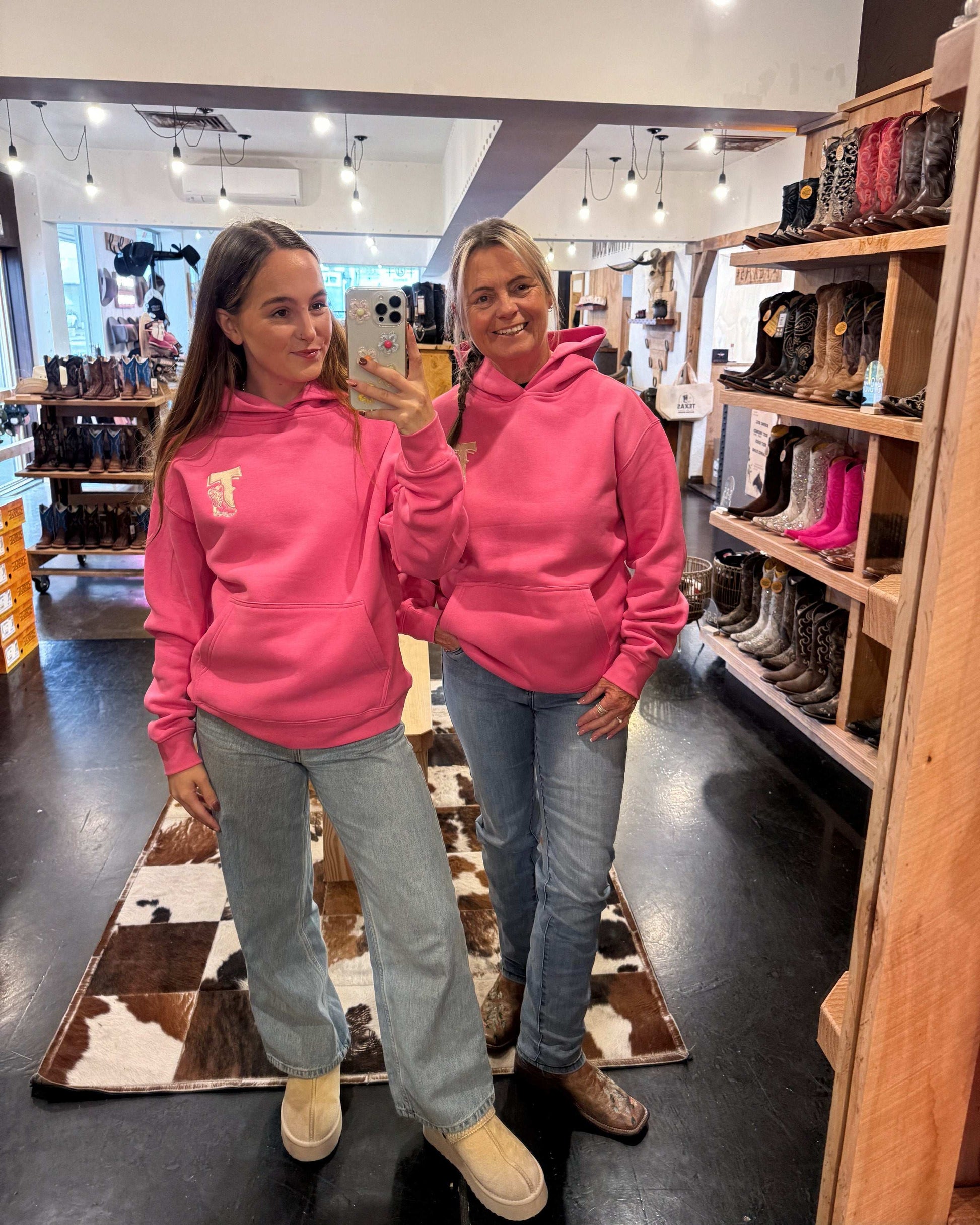 Hot pink Texas Western Apparel hoodie with intricate embroidery. The front features a detailed embroidered 'T' and a Western-style boot, while the back showcases the Texas Western Apparel logo. A bold and stylish statement piece with a classic country flair.