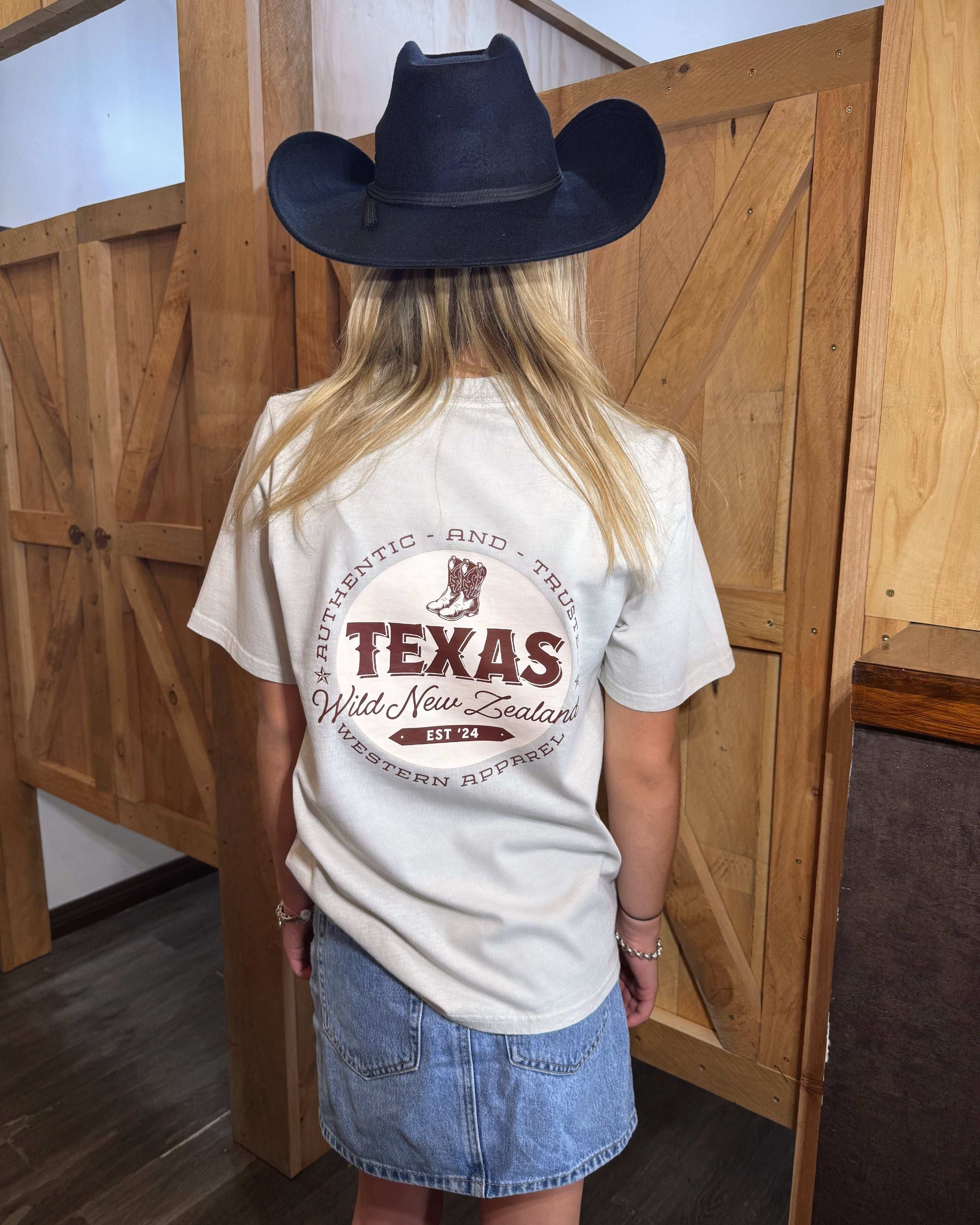 A bone coloured Woman's Texas Western Apparel T-shirt with an embroidered "T" and cowboy boot on the front. The back features "Texas Western Apparel logo.