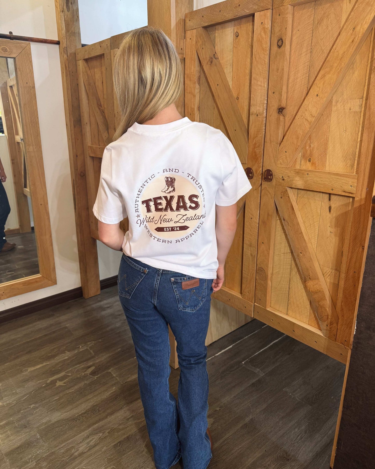 White t-shirt featuring the Texas Western Apparel logo on the front, with a distinctive design that includes bold lettering and western-inspired elements in a stylish, modern font