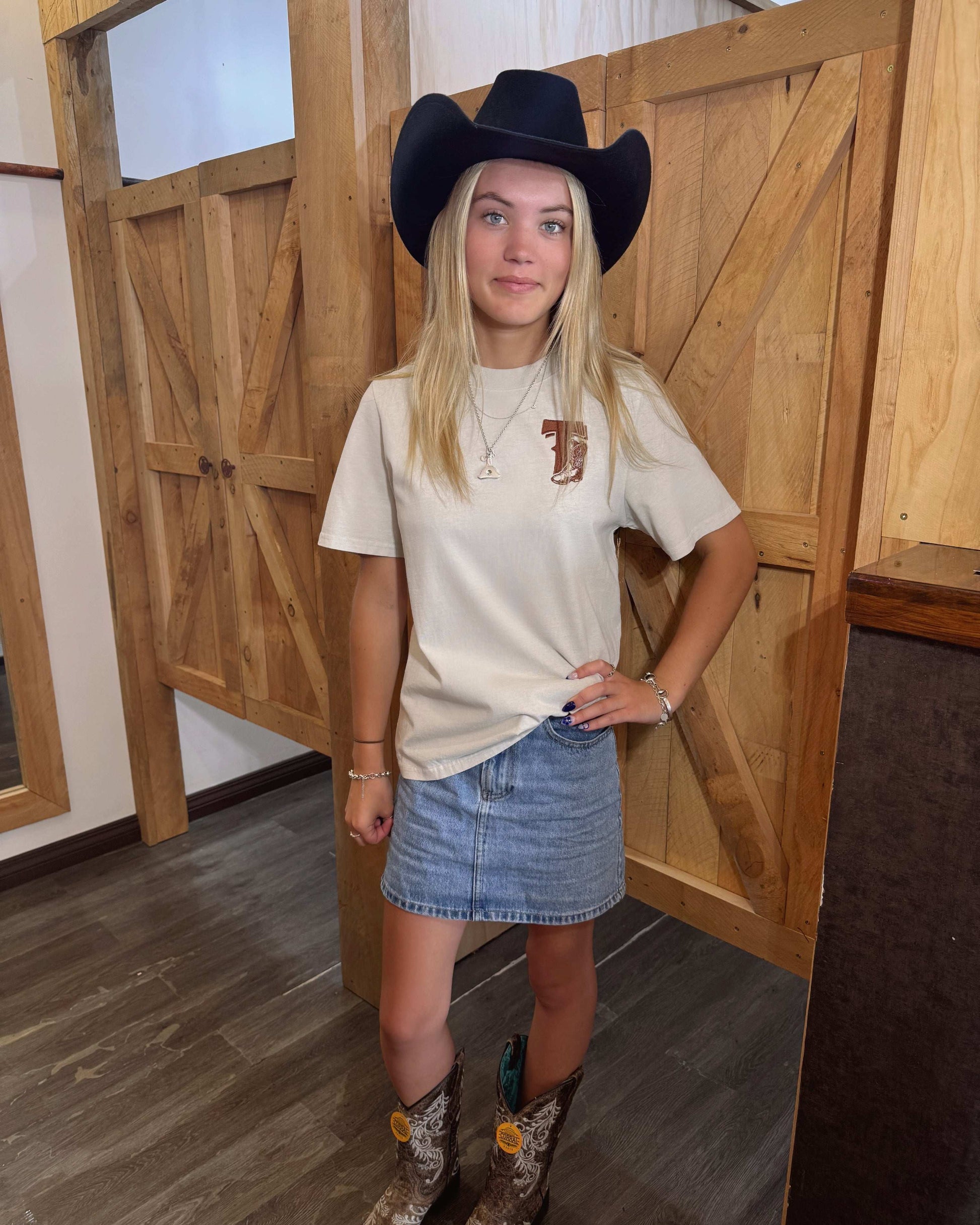 A bone coloured Woman's Texas Western Apparel T-shirt with an embroidered "T" and cowboy boot on the front. The back features "Texas Western Apparel logo.