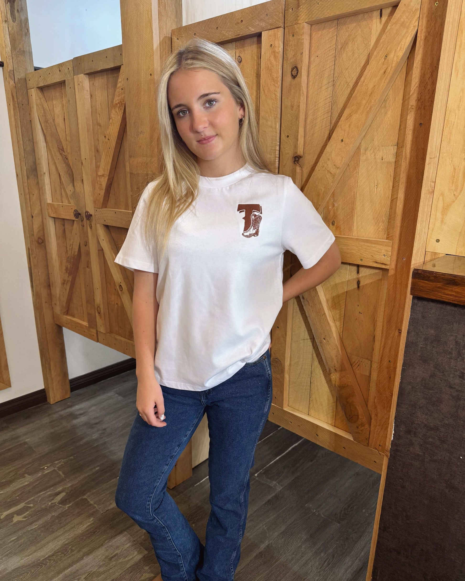 White t-shirt featuring the Texas Western Apparel logo on the front, with a distinctive design that includes bold lettering and western-inspired elements in a stylish, modern font