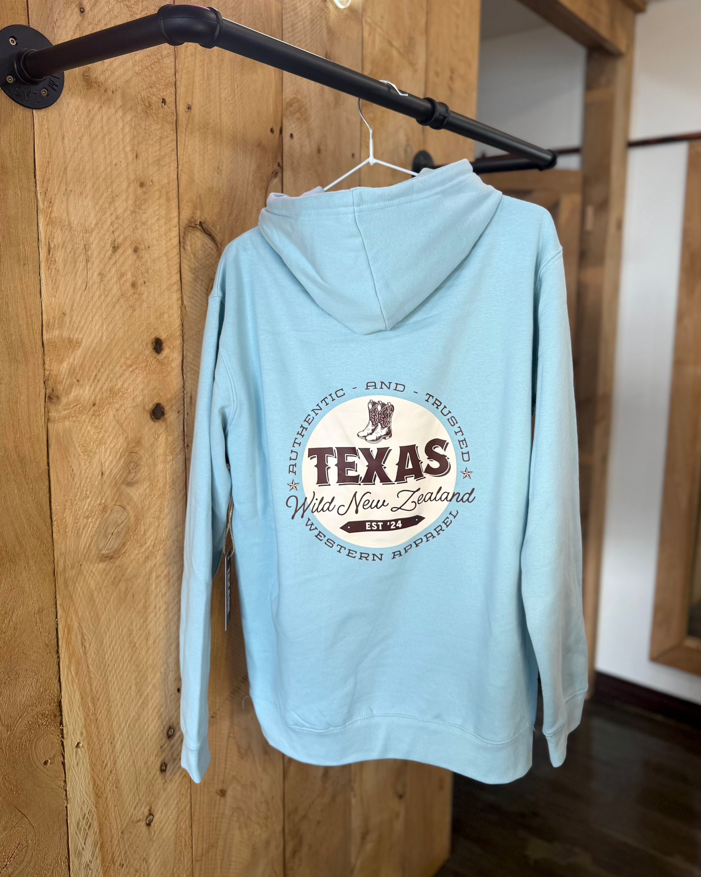 Pale Blue Texas Western Apparel hoodie with intricate embroidery. The front features a detailed embroidered 'T' and a Western-style boot, while the back showcases the Texas Western Apparel logo. A bold and stylish statement piece with a classic country flair.