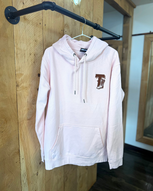 Pale Pink Texas Western Apparel hoodie with intricate embroidery. The front features a detailed embroidered 'T' and a Western-style boot, while the back showcases the Texas Western Apparel logo. A bold and stylish statement piece with a classic country flair.