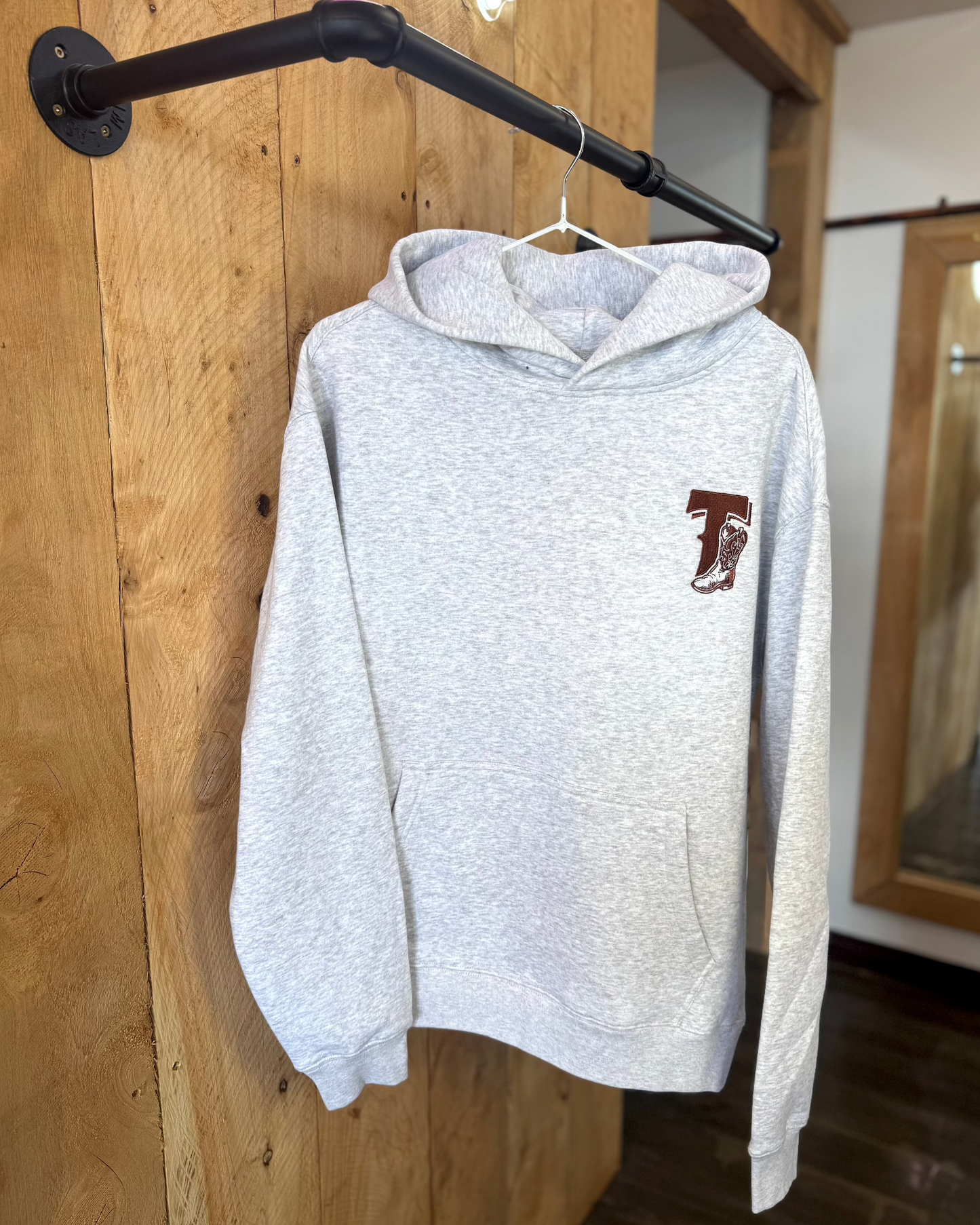 Pale Blue Texas Western Apparel hoodie with intricate embroidery. The front features a detailed embroidered 'T' and a Western-style boot, while the back showcases the Texas Western Apparel logo. A bold and stylish statement piece with a classic country flair.