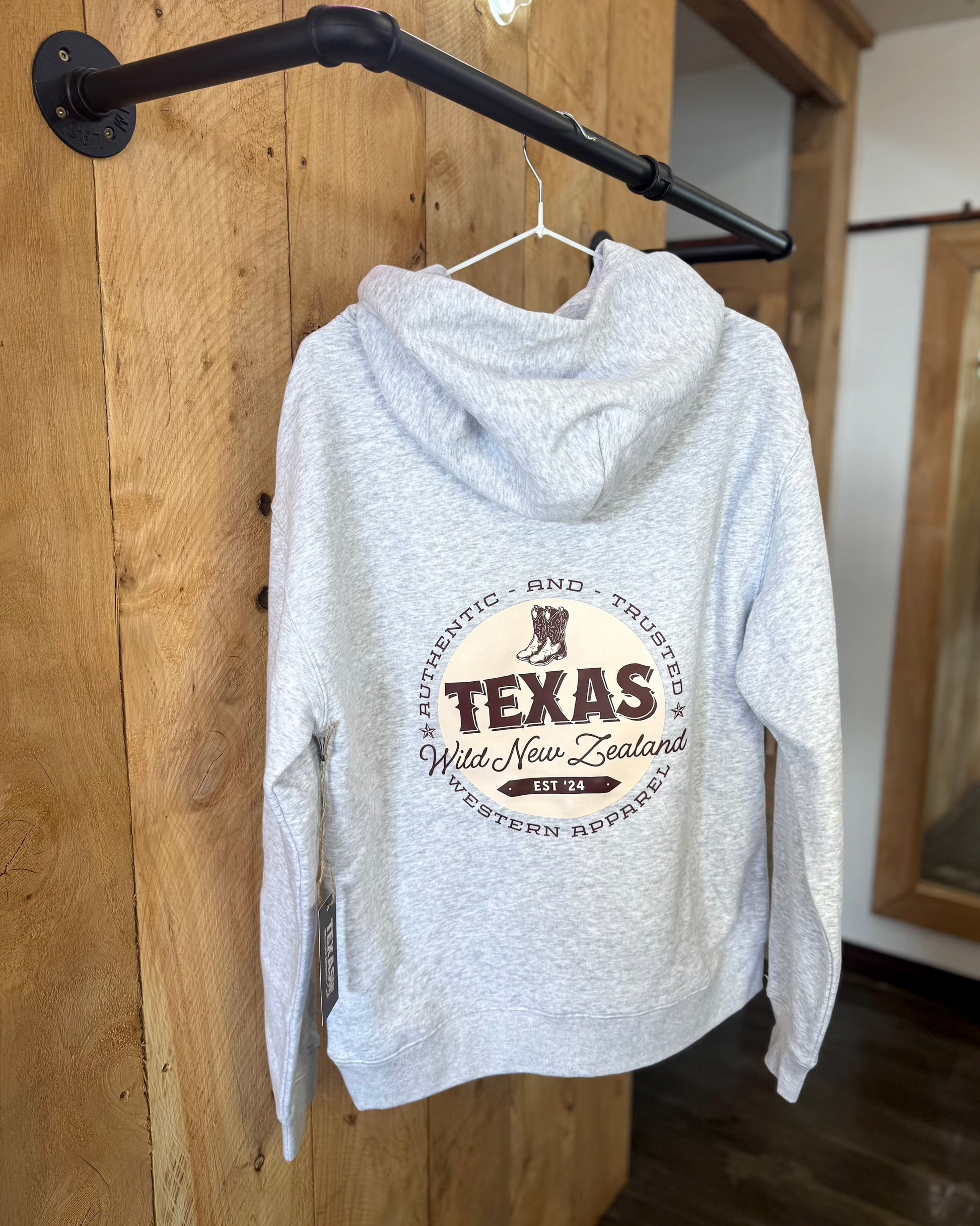 Snow Marle Texas Western Apparel hoodie with intricate embroidery. The front features a detailed embroidered 'T' and a Western-style boot, while the back showcases the Texas Western Apparel logo. A bold and stylish statement piece with a classic country flair.