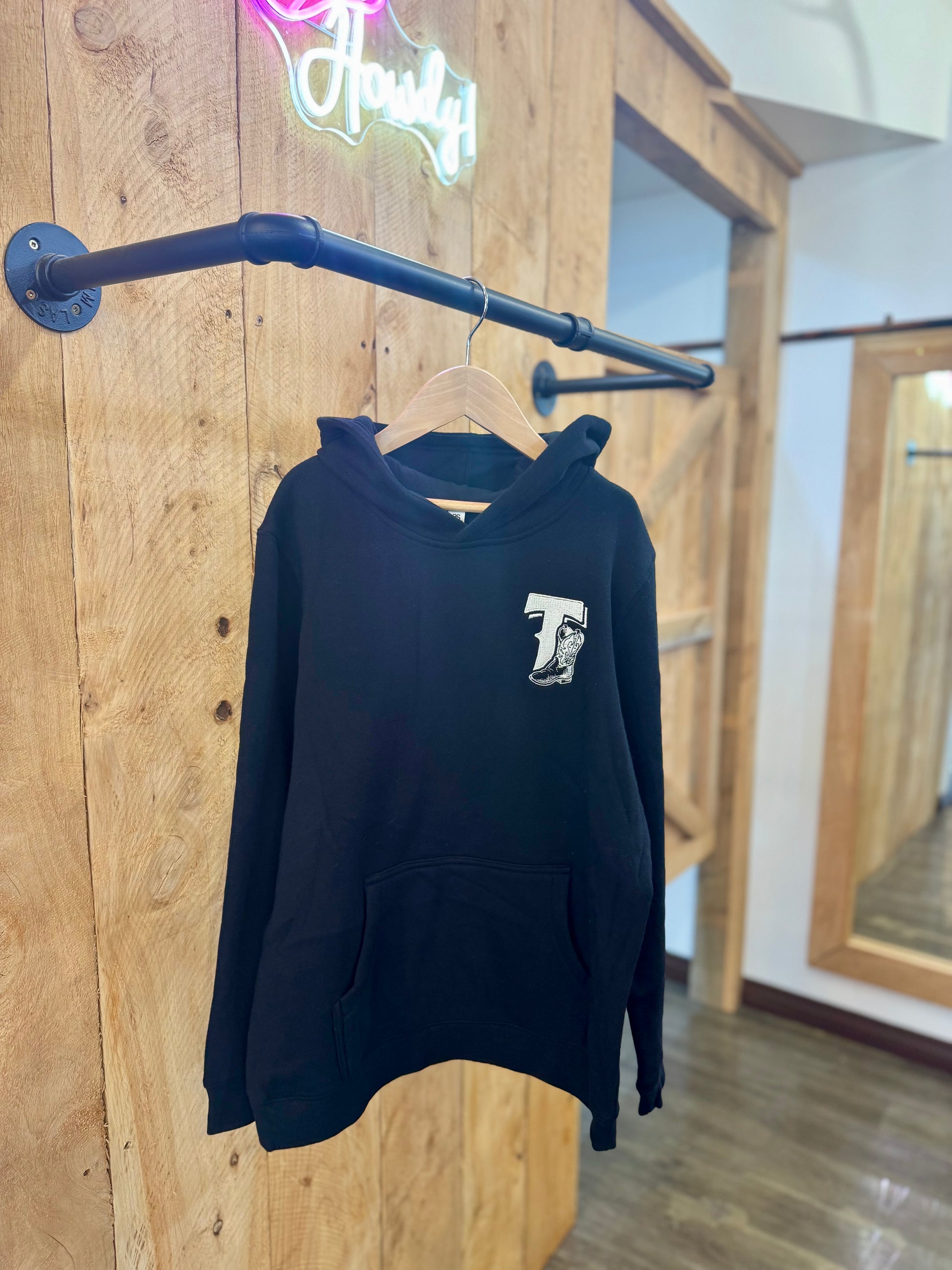 Black Texas Western Apparel youth/kids hoodie with detailed embroidery. The front features a stitched 'T' and a Western-style boot, while the back displays the Texas Western Apparel logo. Perfect for little cowboys and cowgirls who love bold Western style!