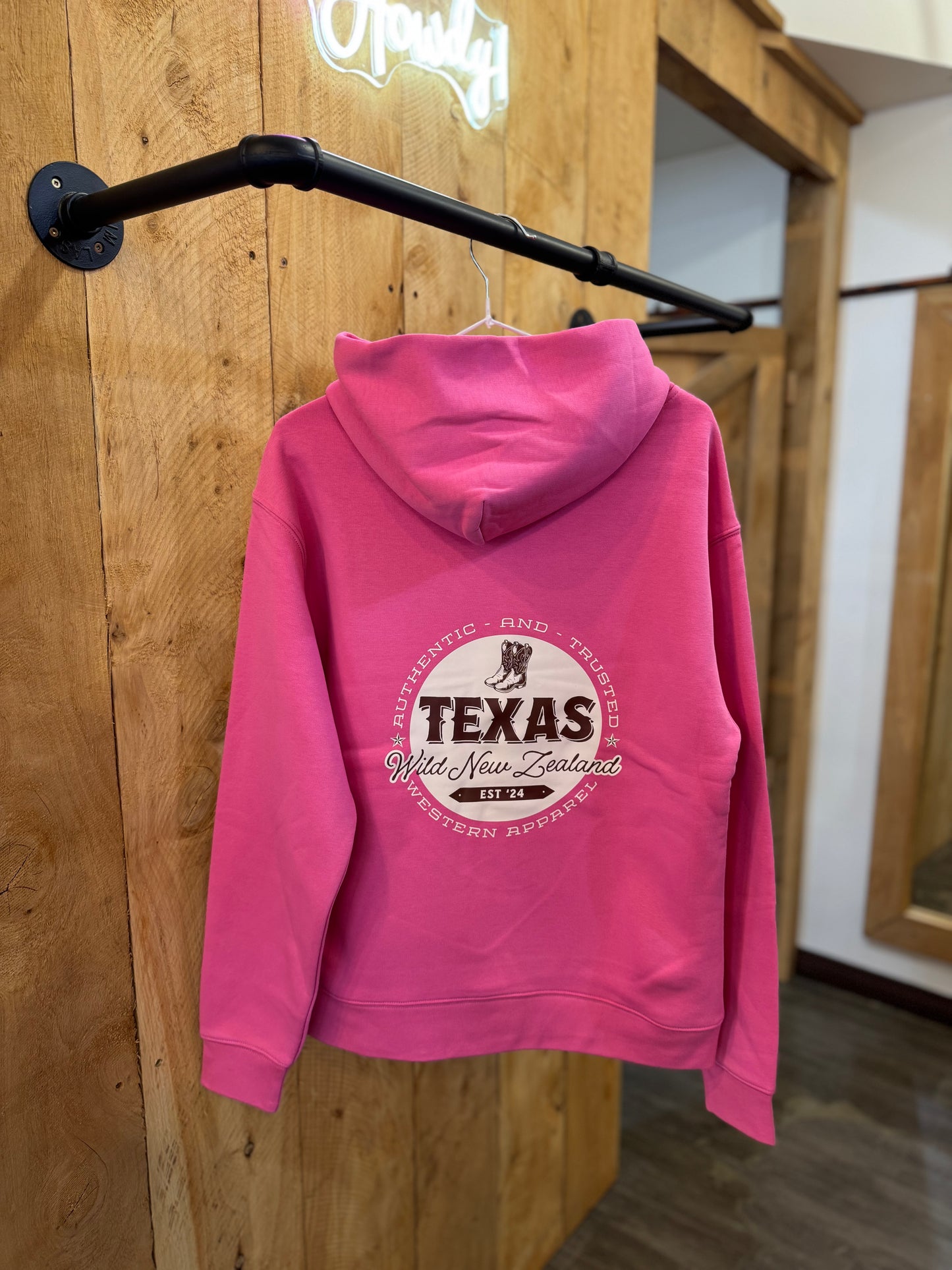 Hot pink Texas Western Apparel hoodie with intricate embroidery. The front features a detailed embroidered 'T' and a Western-style boot, while the back showcases the Texas Western Apparel logo. A bold and stylish statement piece with a classic country flair.