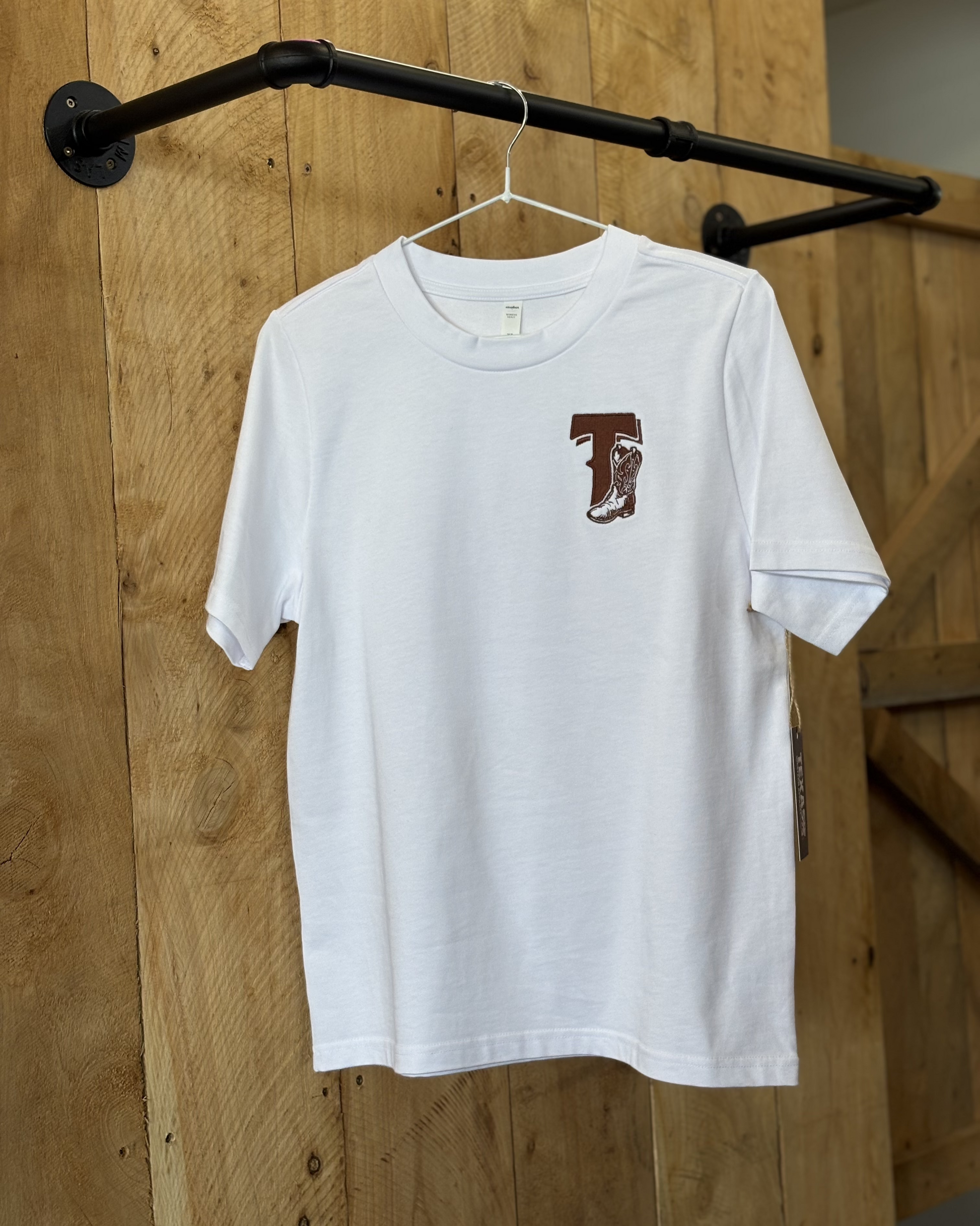 White t-shirt featuring the Texas Western Apparel logo on the front, with a distinctive design that includes bold lettering and western-inspired elements in a stylish, modern font