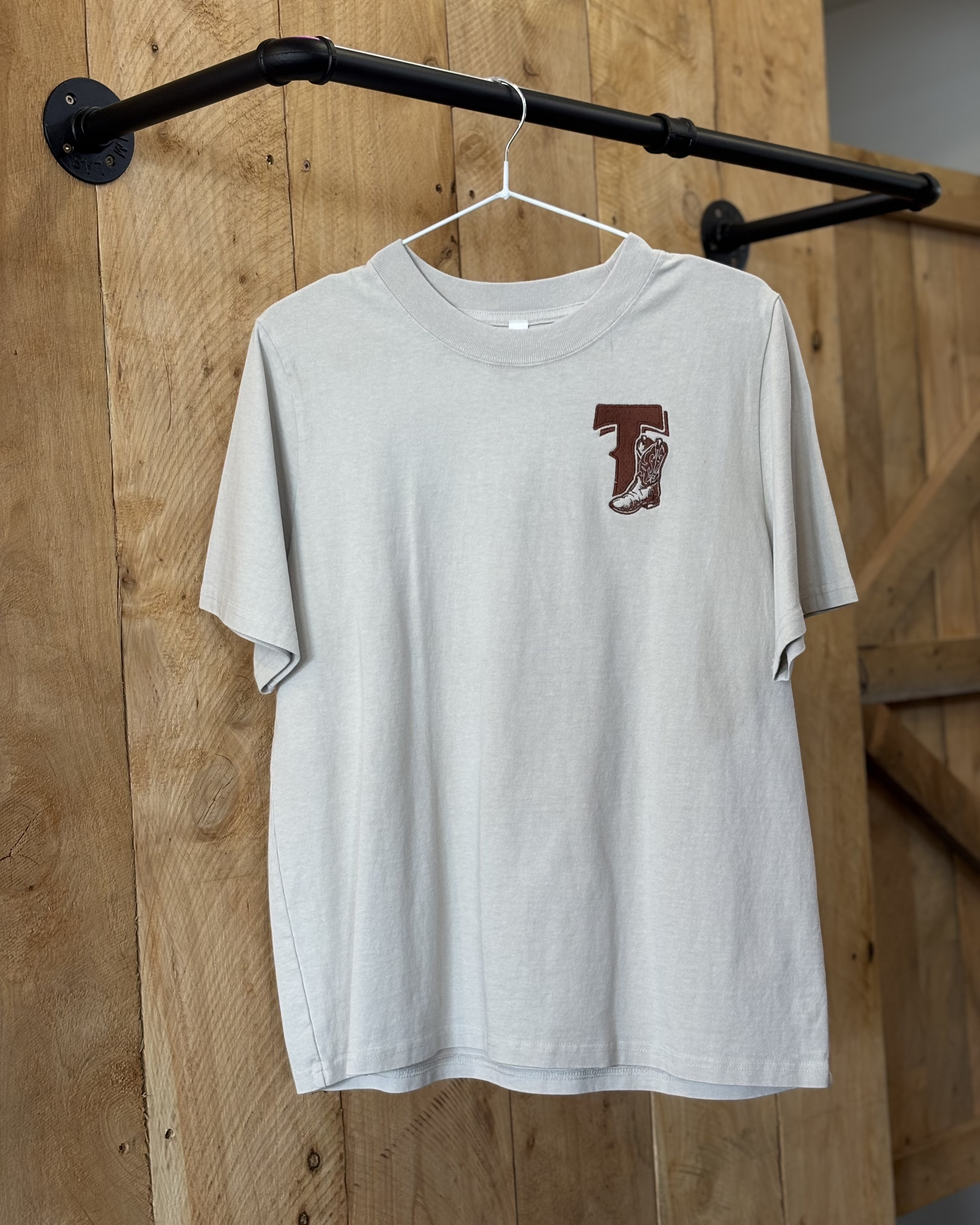 A bone coloured Woman's Texas Western Apparel T-shirt with an embroidered "T" and cowboy boot on the front. The back features "Texas Western Apparel logo.