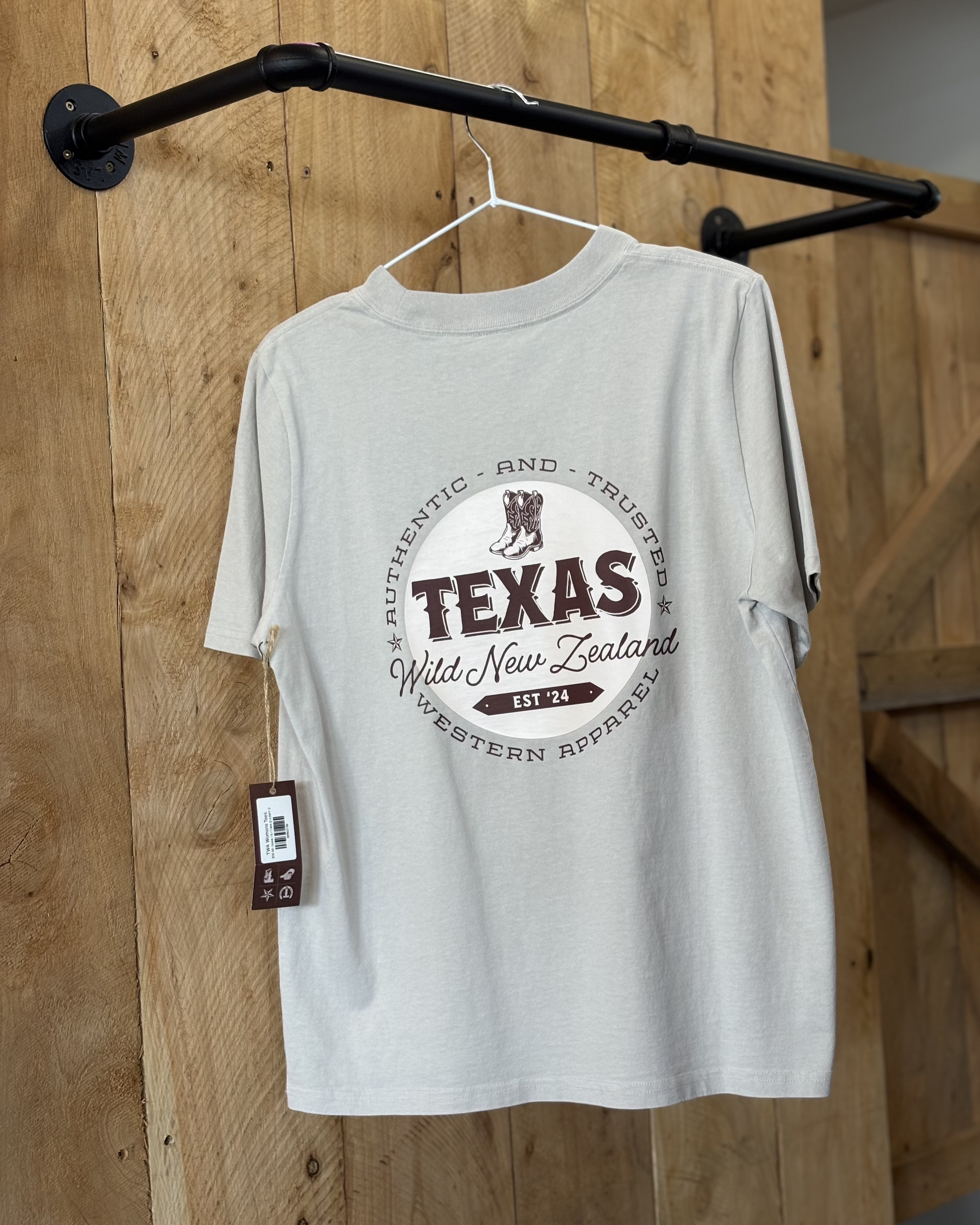 A bone coloured Woman's Texas Western Apparel T-shirt with an embroidered "T" and cowboy boot on the front. The back features "Texas Western Apparel logo.