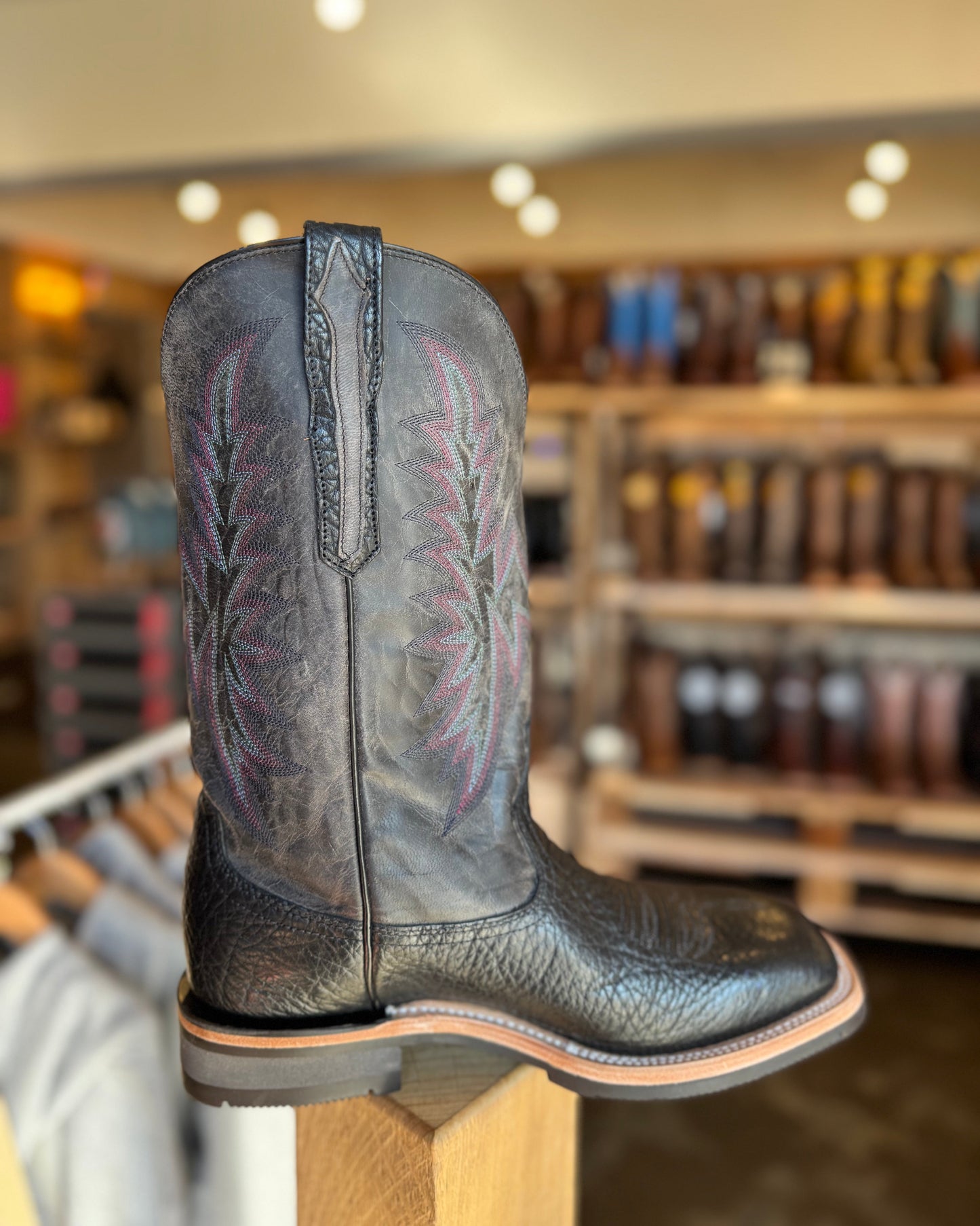 Black cowboy boot on a stand with a store interior in the background