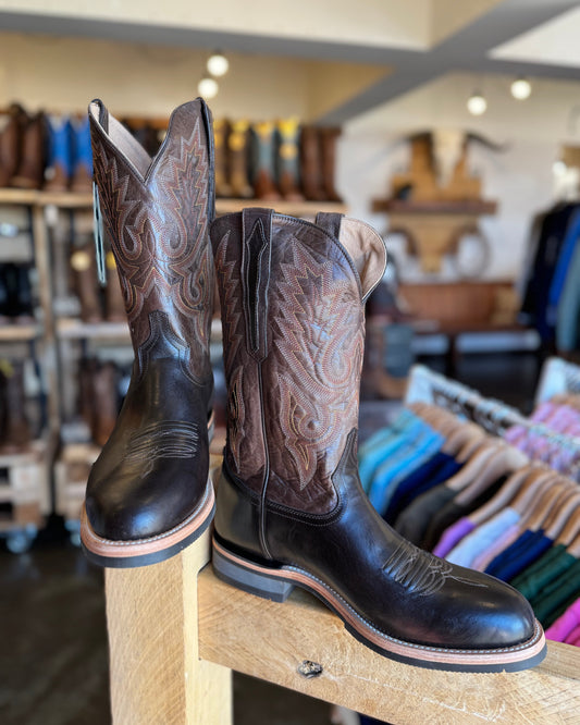 Pair of cowboy boots on a wooden stool in a store setting with blurred background