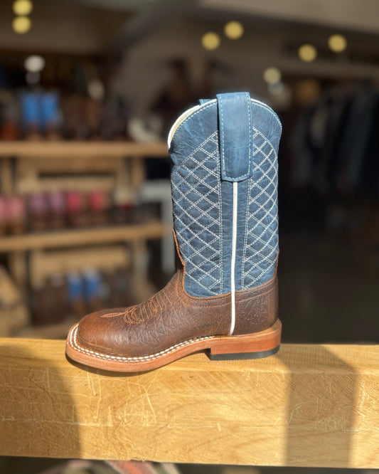 Brown cowboy boot with blue quilted pattern on a wooden surface in a store setting
