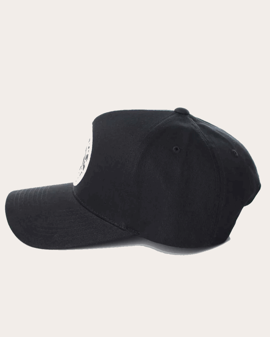 A black snapback cap featuring a structured six-panel design with a curved brim. The front panel showcases a circular embroidered patch with 'Ringers Western' text and a bull silhouette in white. The back of the cap includes an adjustable snap closure.