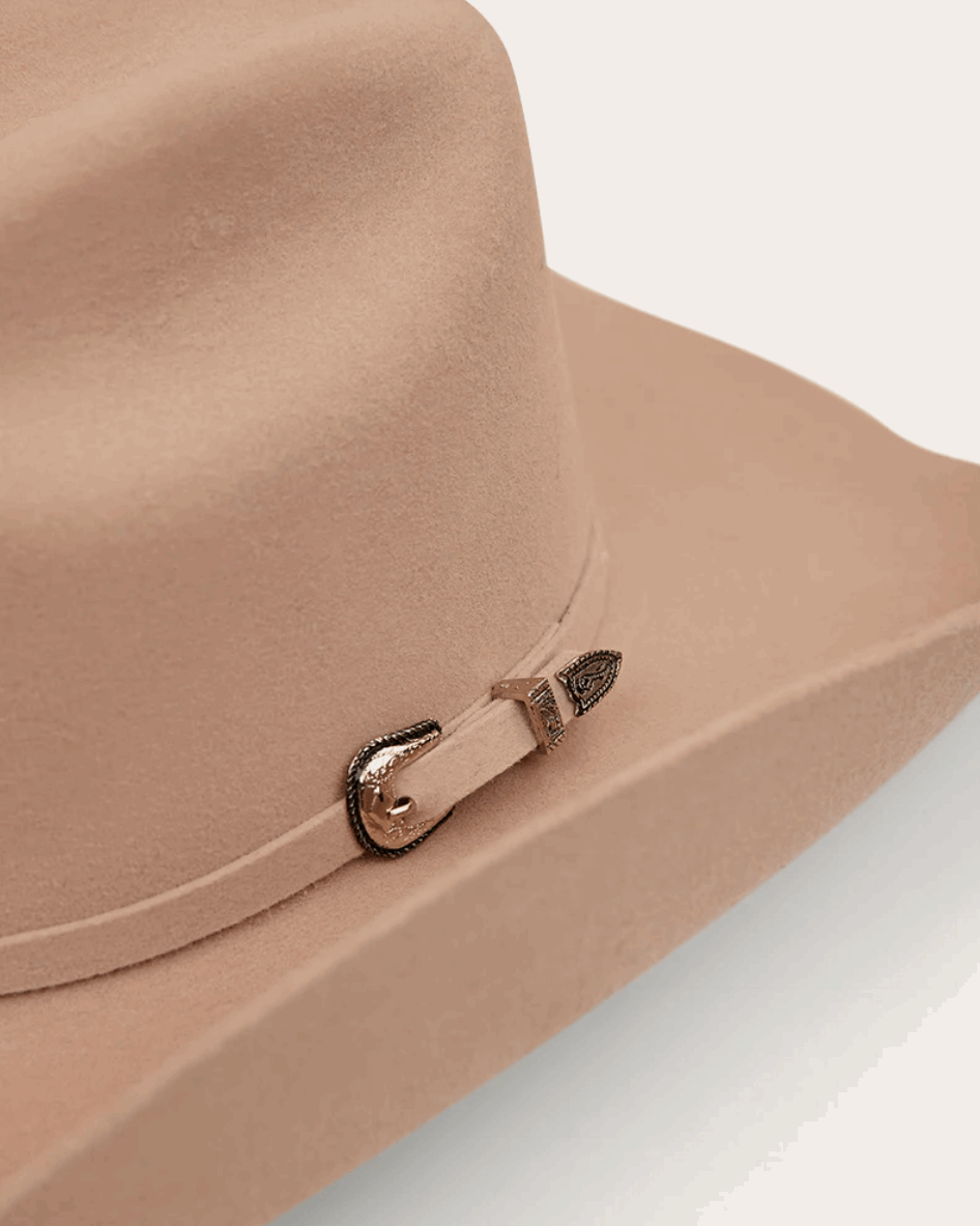 A classic beige cowboy hat by Ringers Western, made of premium felt with a structured crown and a wide, upturned brim. A silver buckle accent on the hatband adds a refined touch.