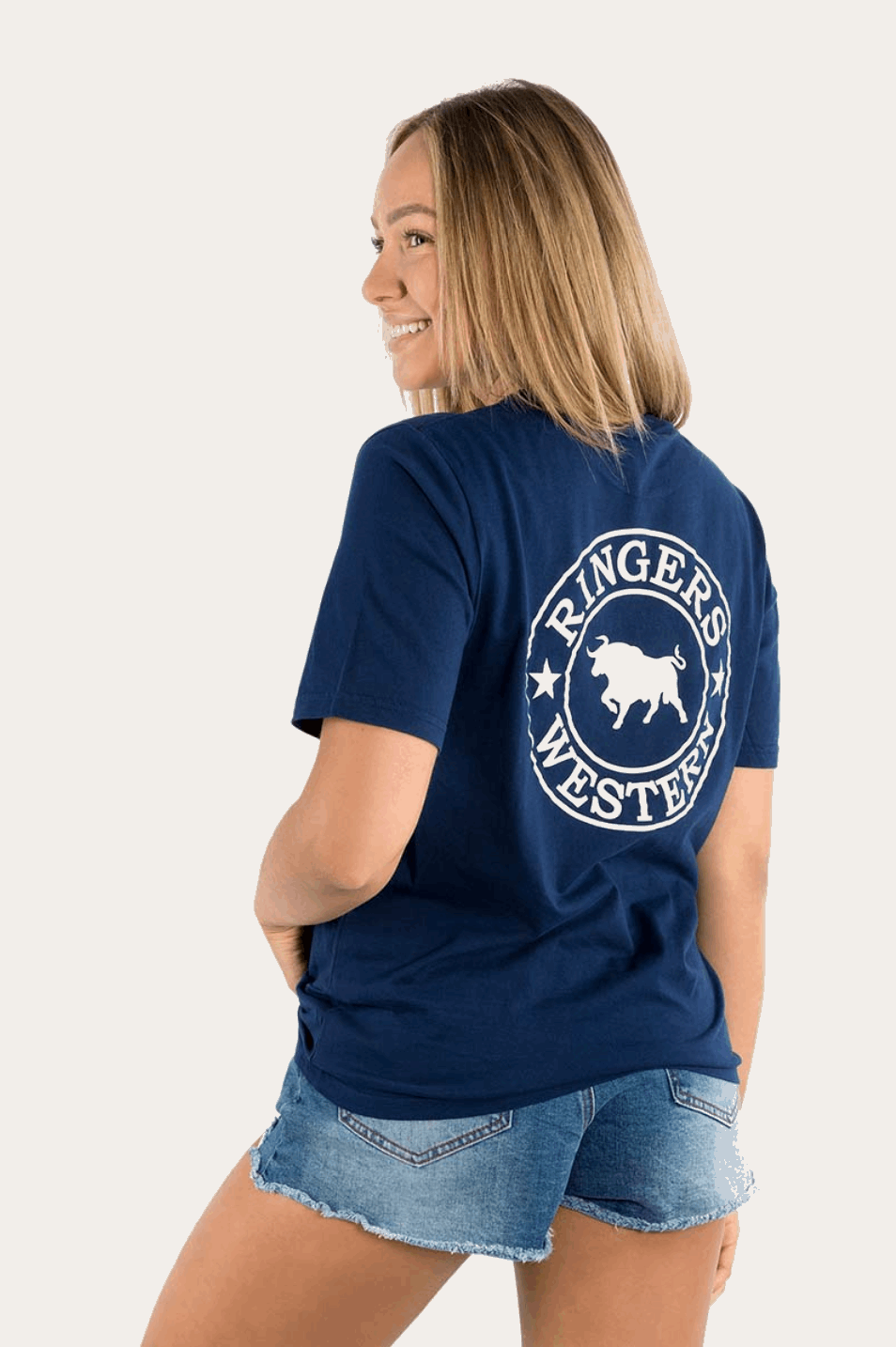 A navy blue Ringers Western T-shirt with a classic crew neck and relaxed fit. The front features a small white circular logo on the left chest with a bull design and "Ringers Western" text. The back showcases a larger version of the same logo, prominently displayed in white. The T-shirt is styled with distressed denim shorts for a casual western-inspired look.