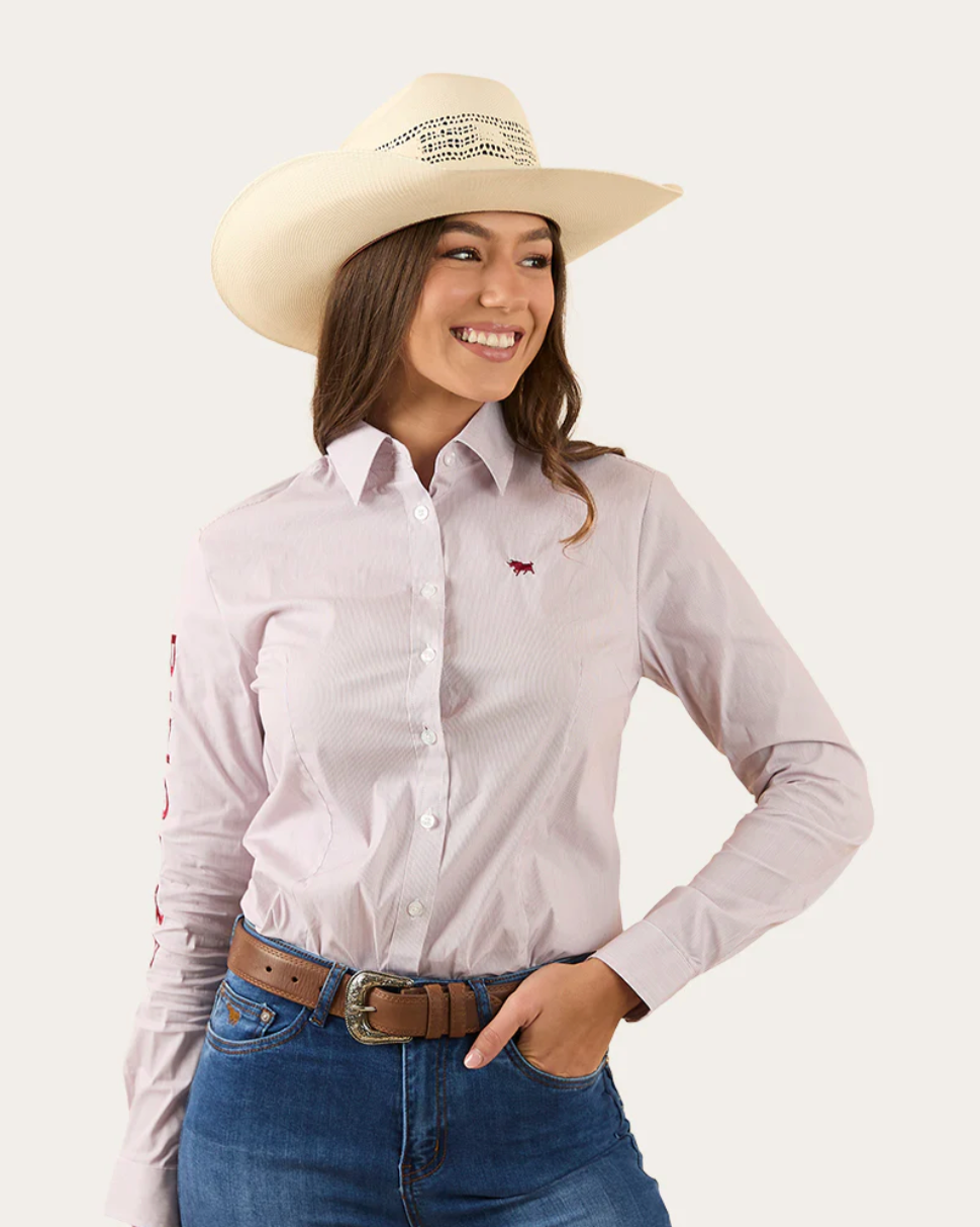 Woman wearing a light purple button-up shirt, blue jeans, and a beige cowboy hat on a white background