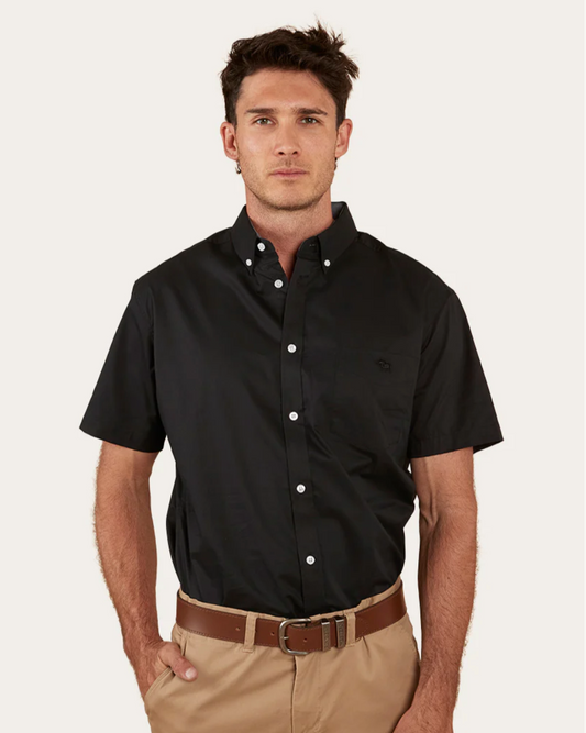 Man wearing a black short-sleeve shirt and beige pants on a white background