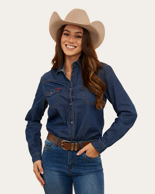 Woman wearing a blue denim shirt, jeans, and a beige cowboy hat on a light gray background