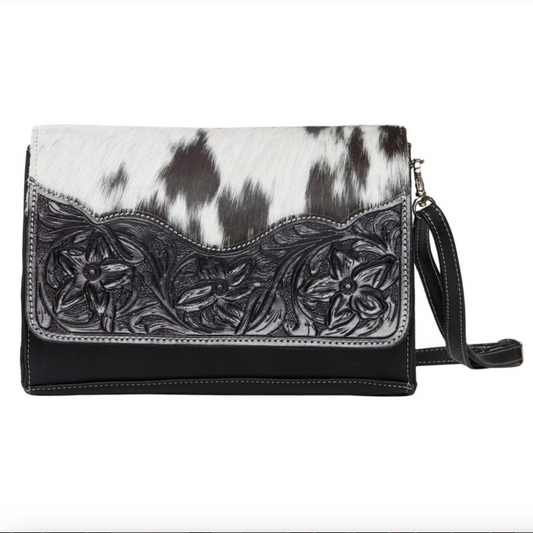 Black and white cowhide handbag with floral embossing on a white background