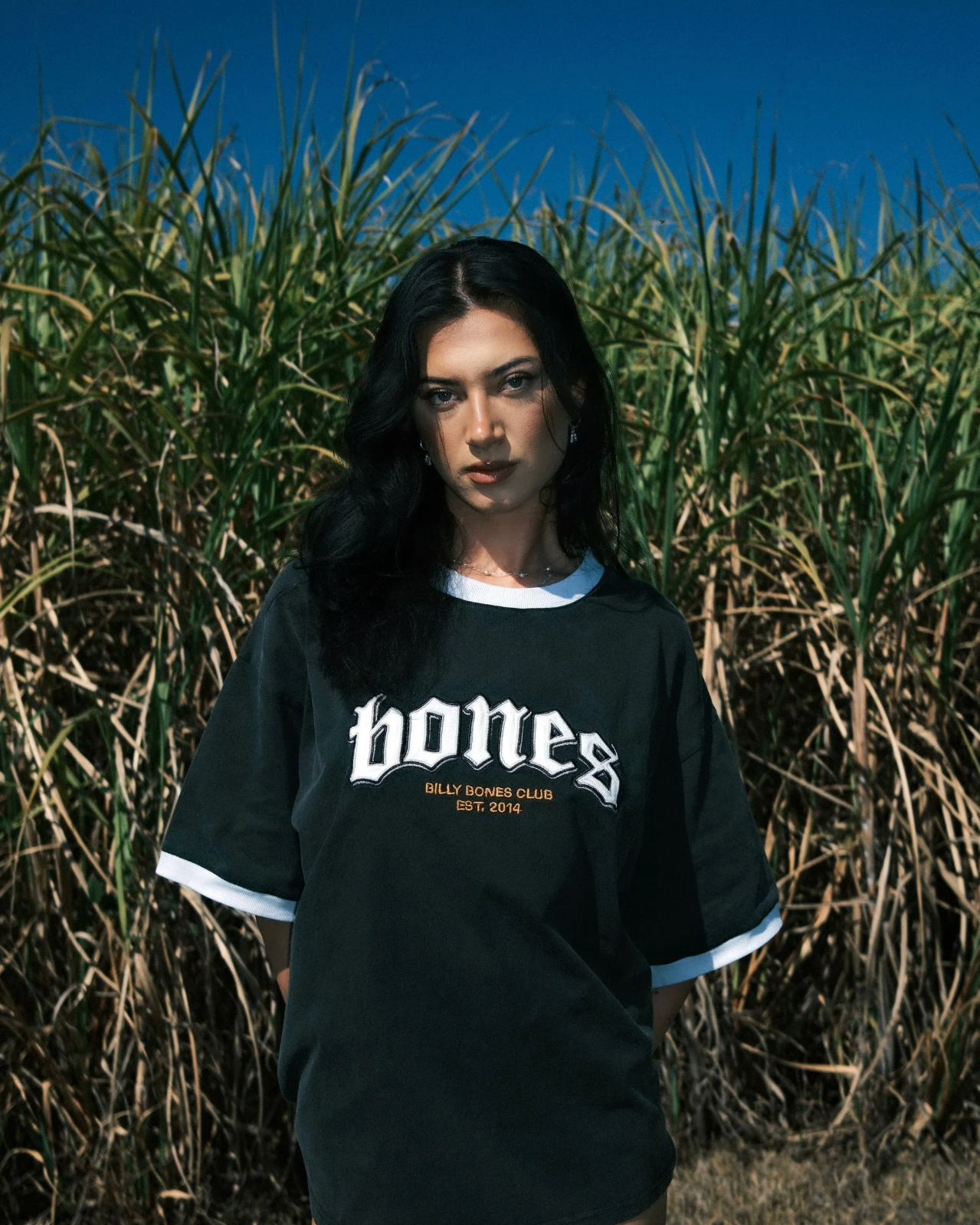 Person wearing a black 'bones' sweatshirt in a field of tall grass