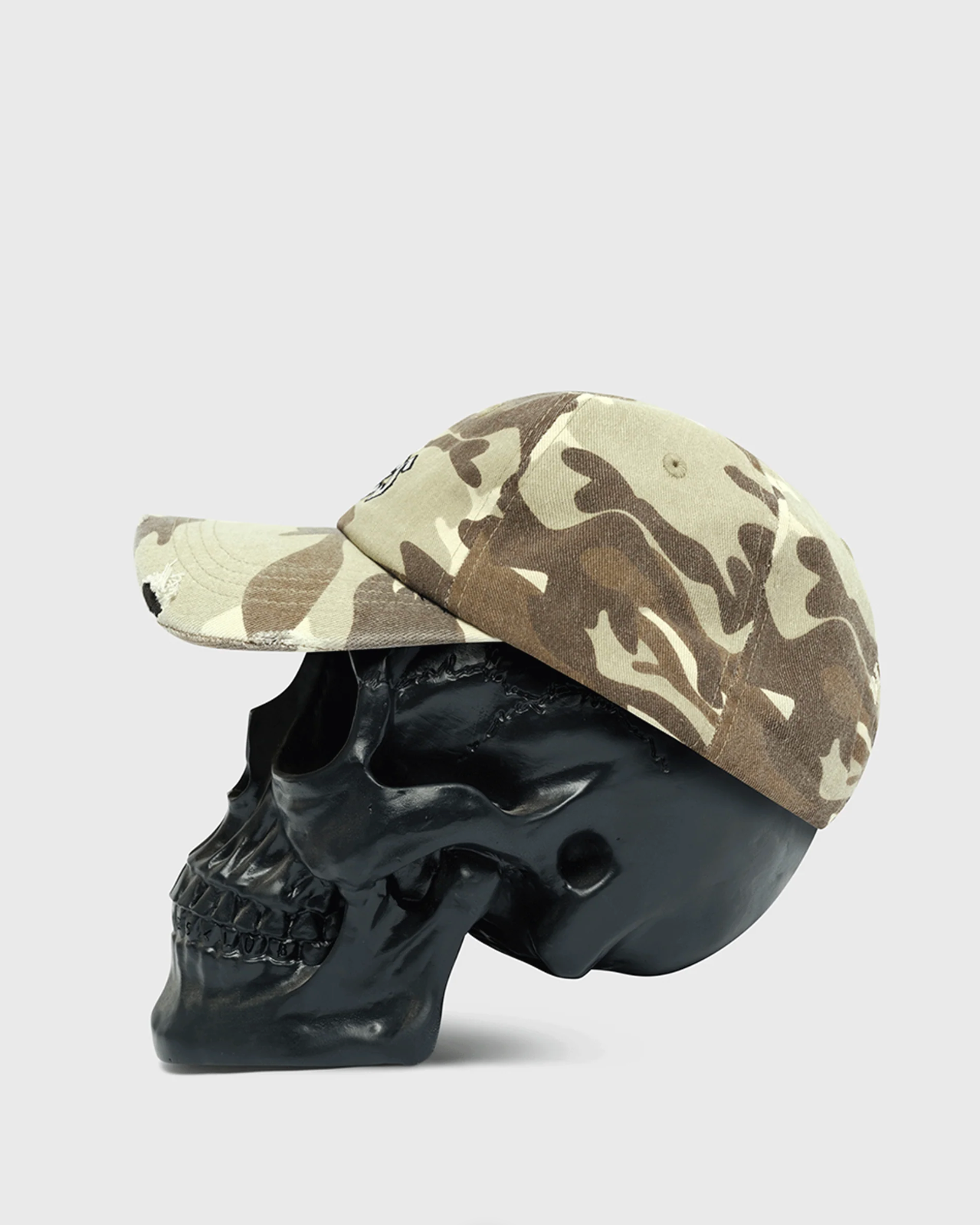 Camouflage baseball cap on a black skull against a white background