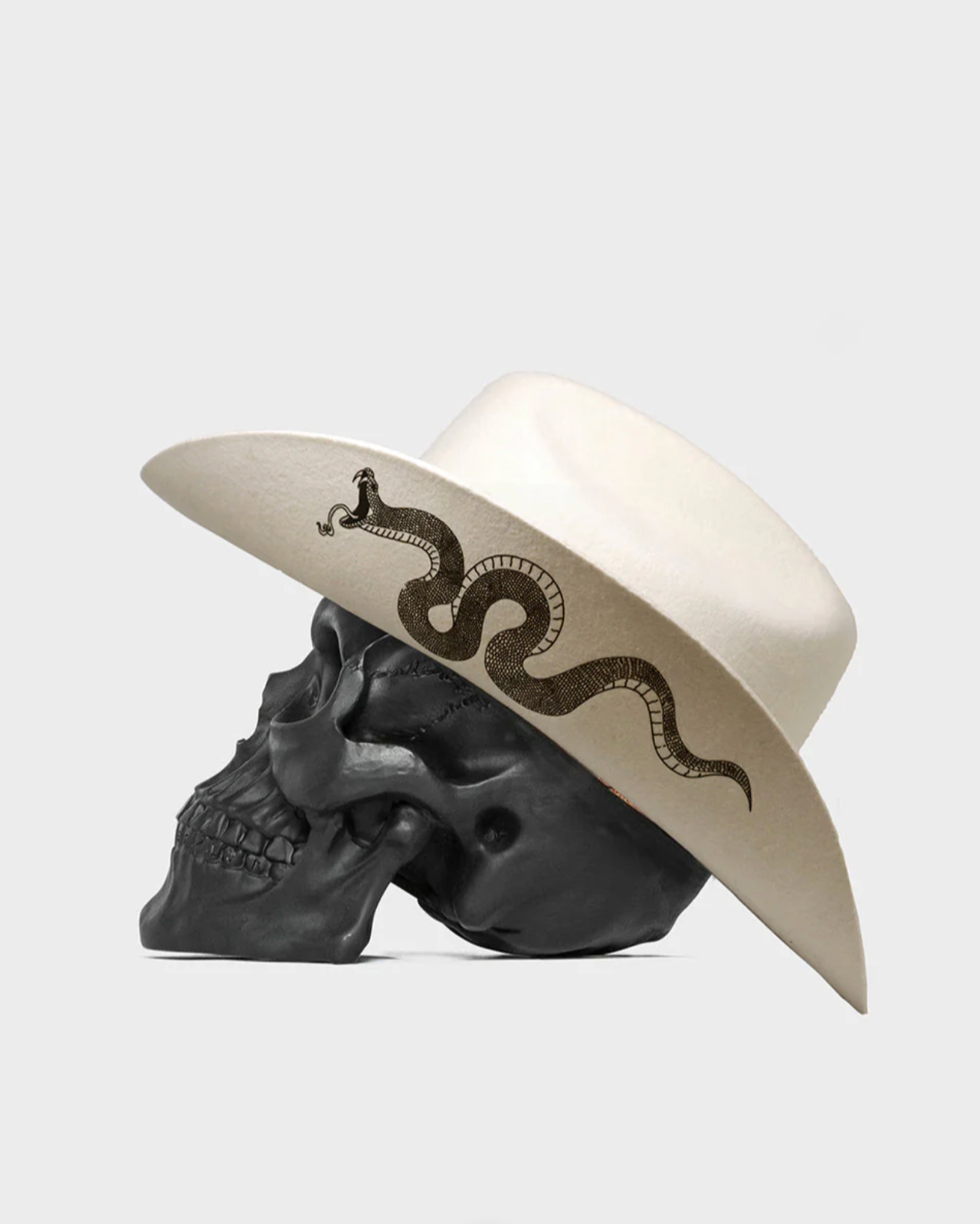 White hat with snake design on a black skull against a light gray background