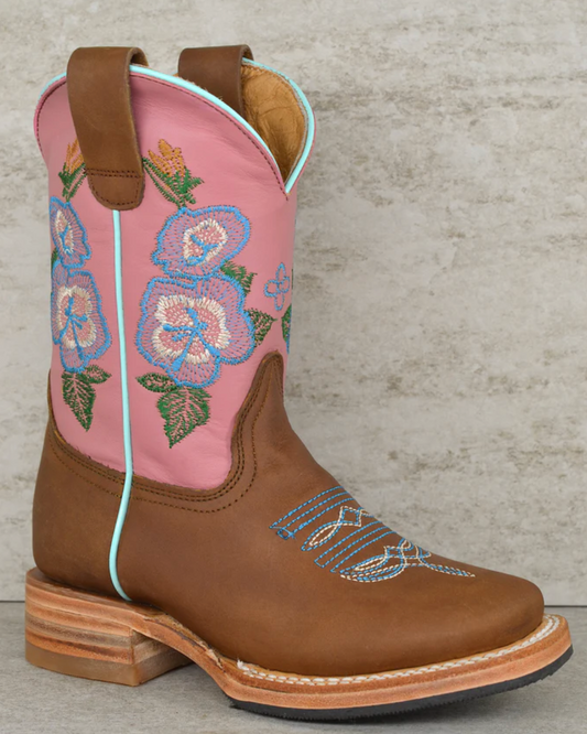 Pink cowboy boot with floral embroidery on a textured surface