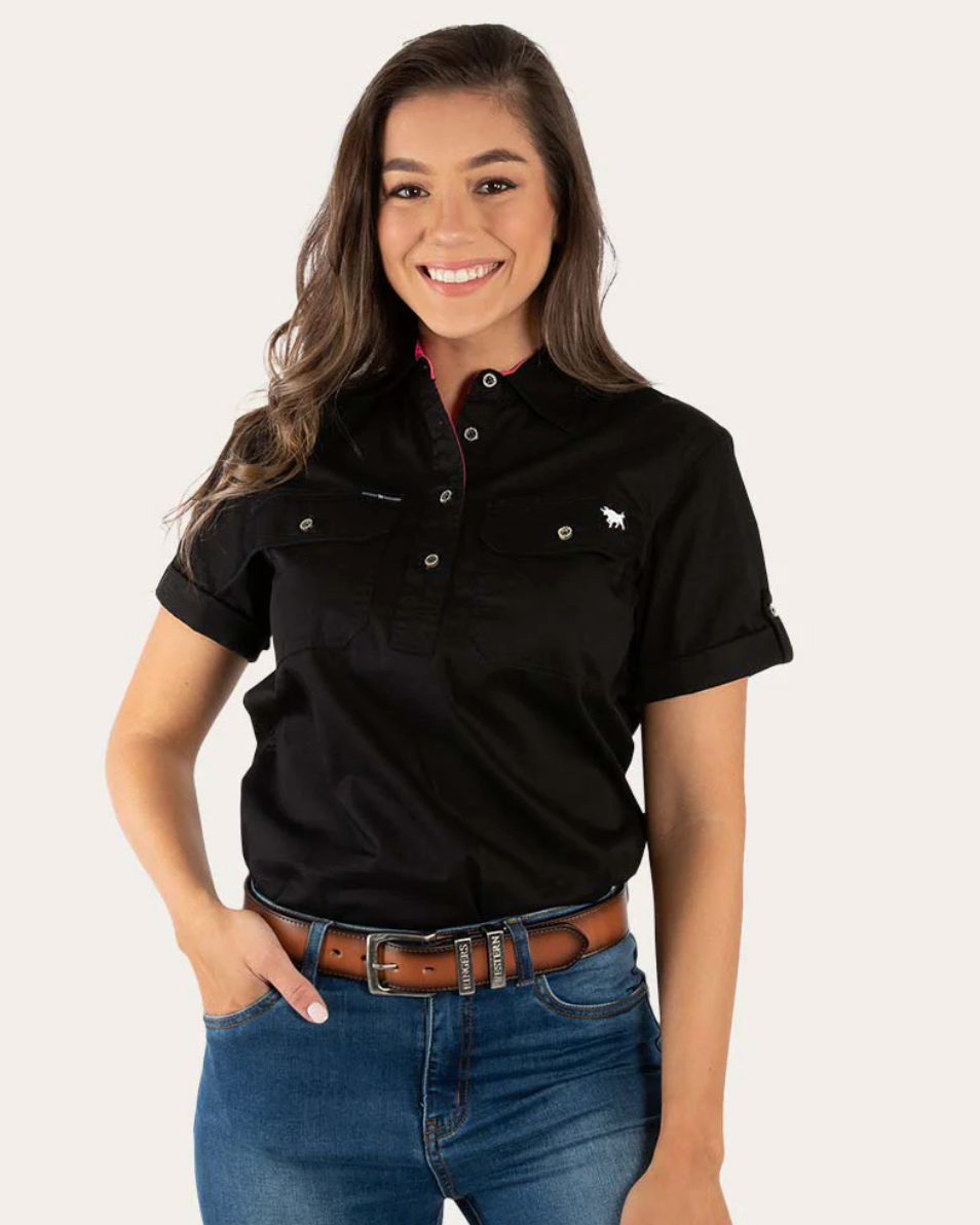 Woman wearing a black polo shirt with a logo and blue jeans on a white background