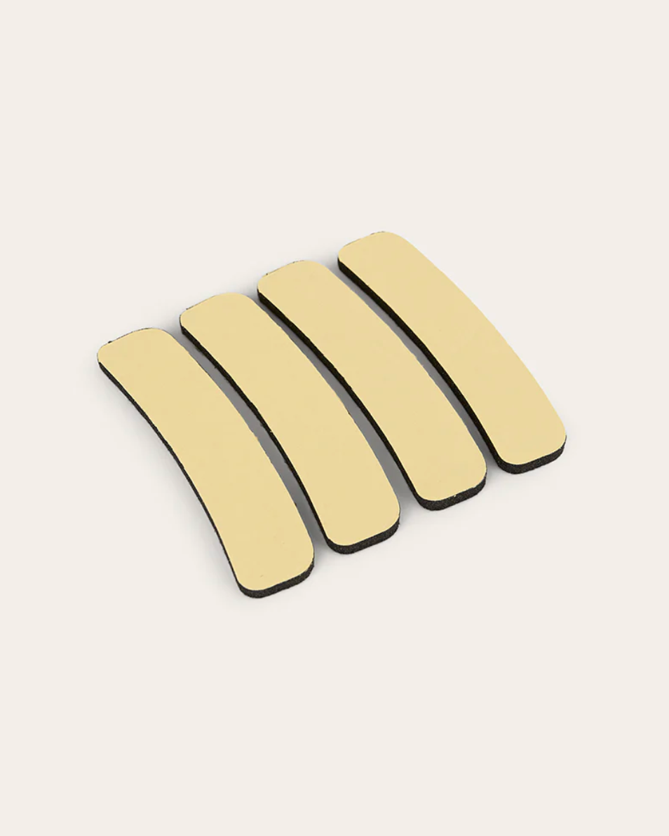 Four beige hair clips arranged in a row on a white background