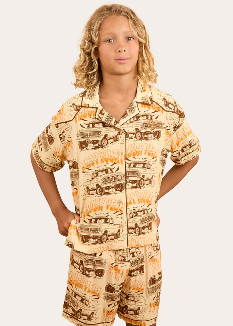 Child wearing a pajama set with truck pattern on a plain background