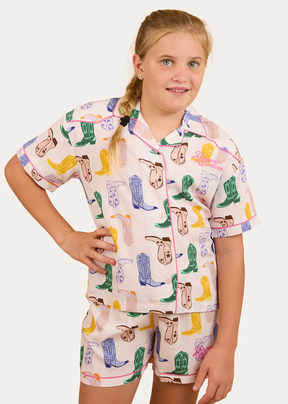 Young girl wearing a pajama set with cowboy boot pattern on a white background
