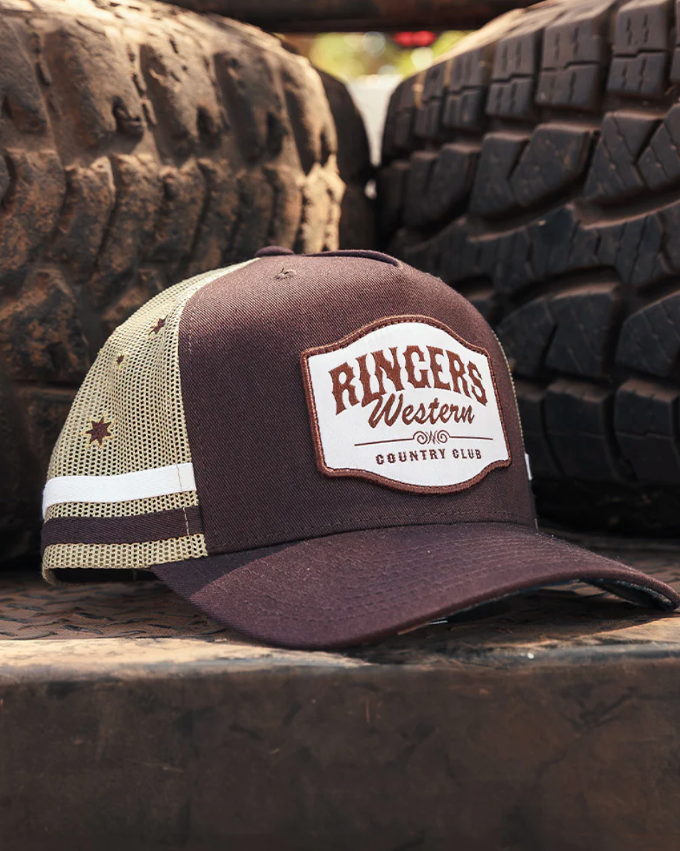 Cap with 'Ringers Western Country Club' logo on a truck bed with tires in the background