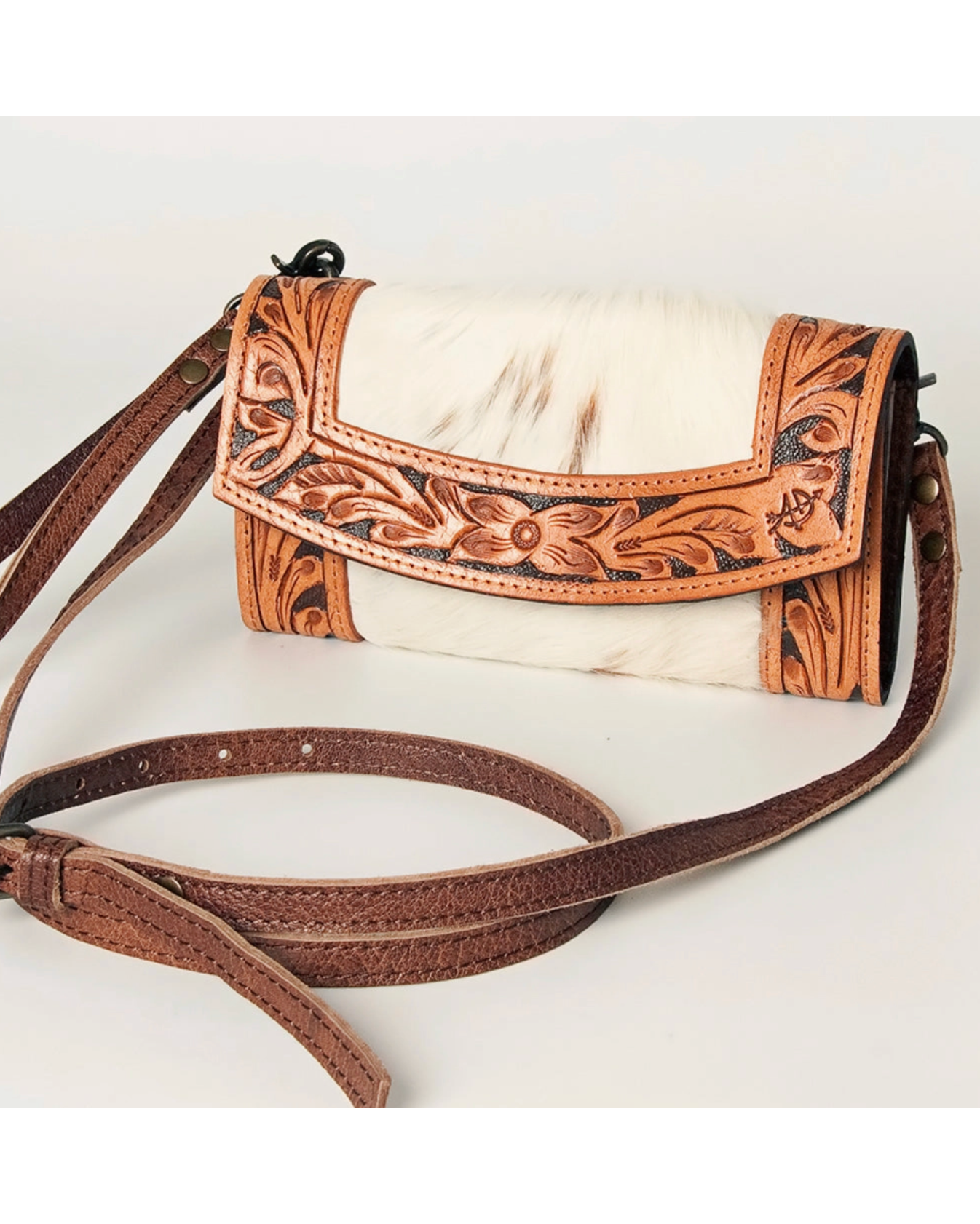 Brown leather handbag with intricate designs on a white background