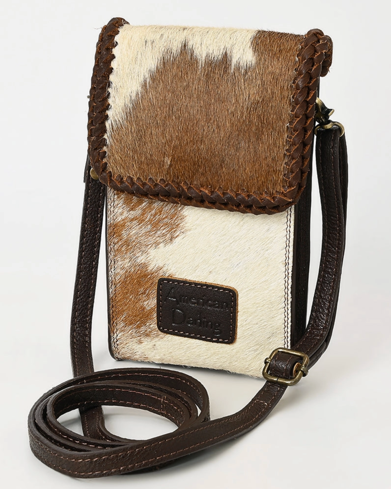 Small crossbody bag with brown and white cowhide leather on a white background