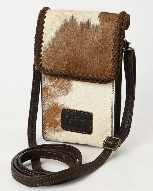 Small crossbody bag with brown and white cowhide leather on a white background