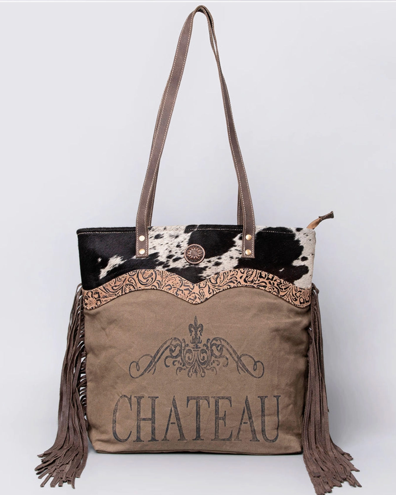 Brown tote bag with cowhide accents and 'Chateau' branding on a white background
