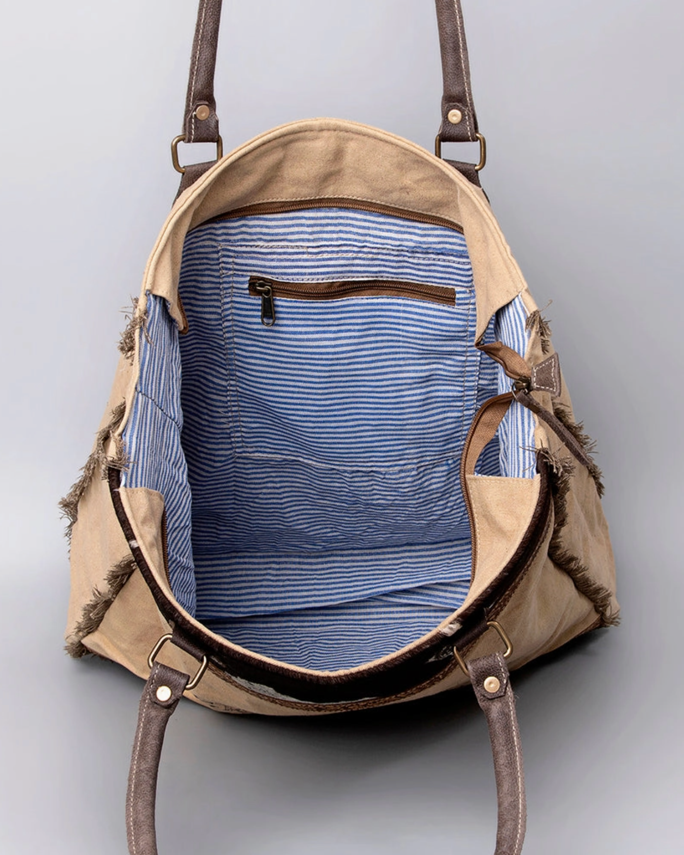 Brown leather backpack with blue interior lining on a gray background