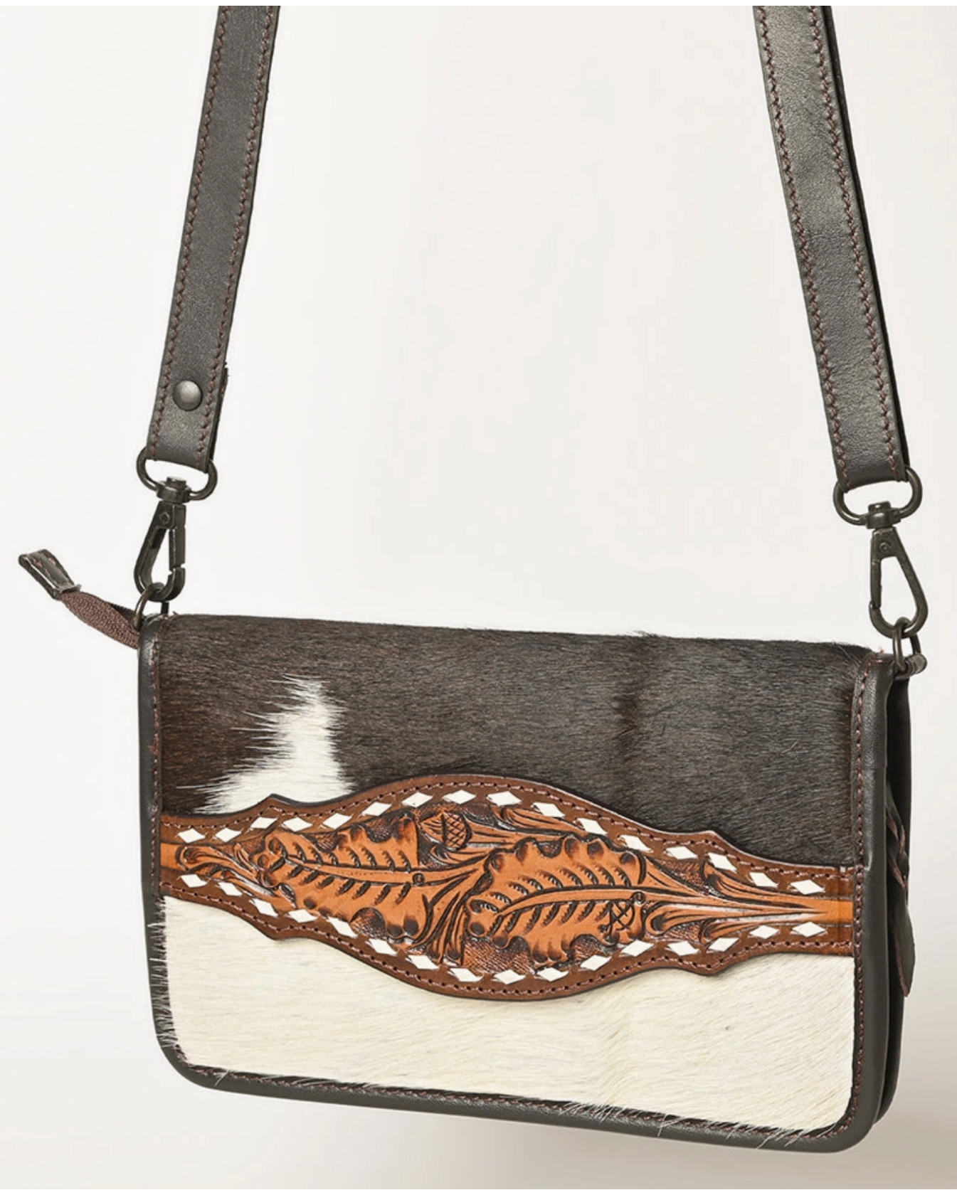 Handbag with cowhide design and brown leather strap on a white background