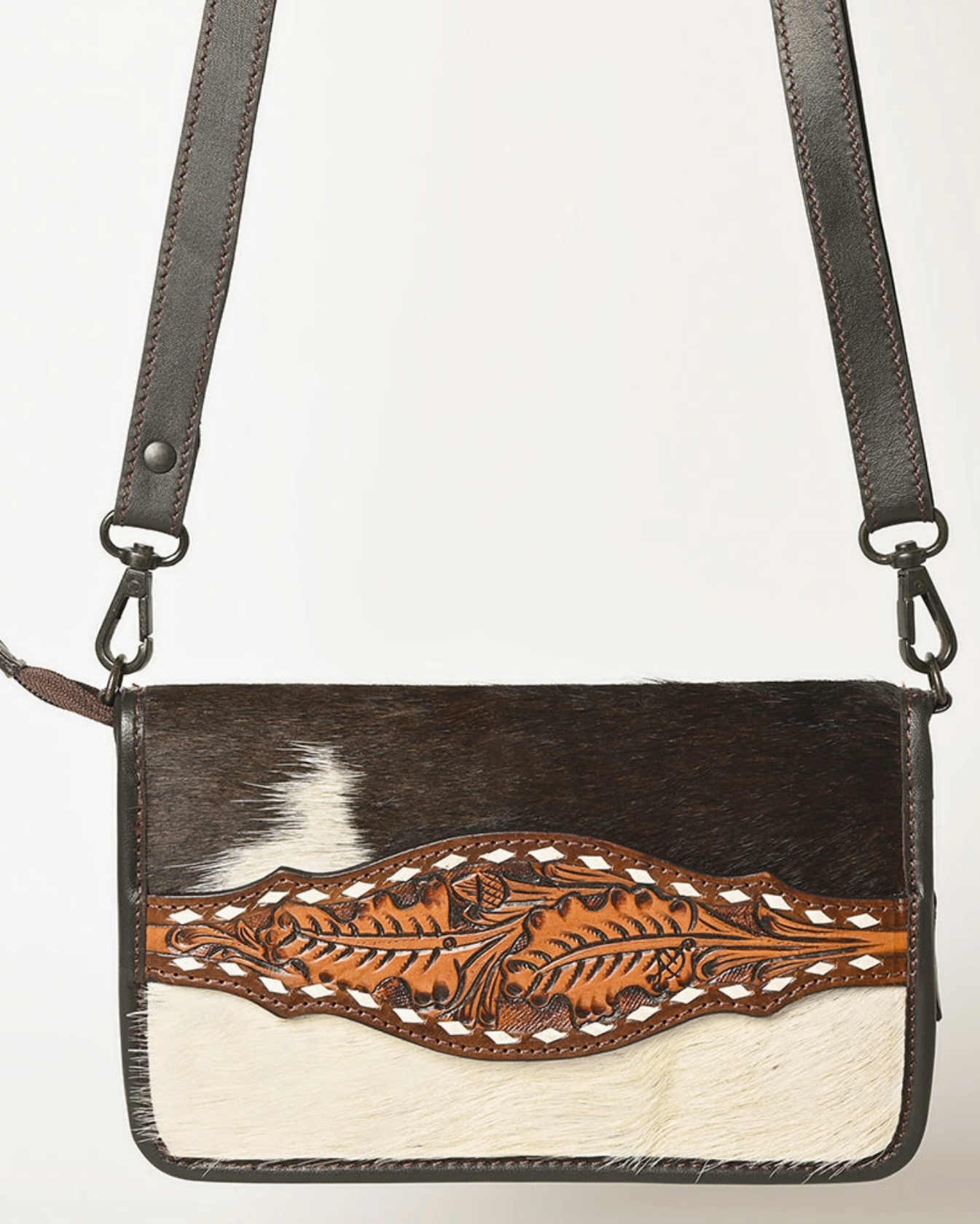 Horsehair crossbody bag with leather strap and floral tooling on a white background