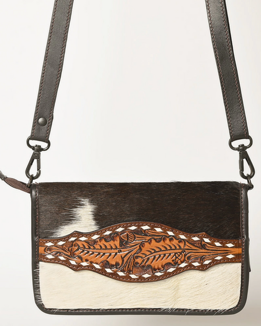 Horsehair crossbody bag with leather strap and floral tooling on a white background