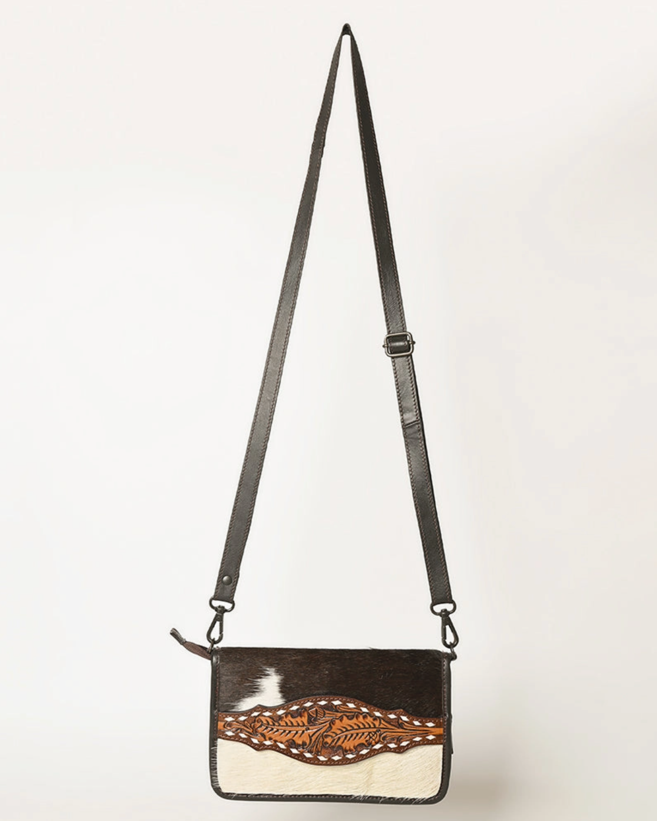 Crossbody bag with cowhide design and leather strap on a white background