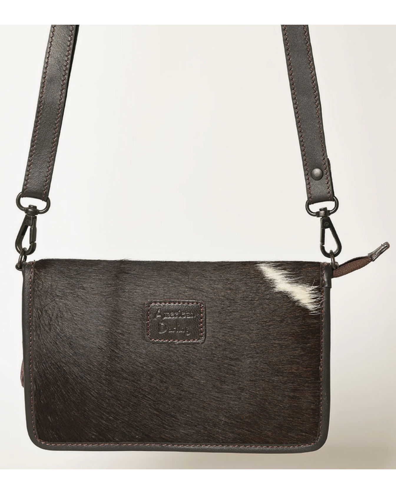 Black leather crossbody bag with cowhide texture on a light gray background