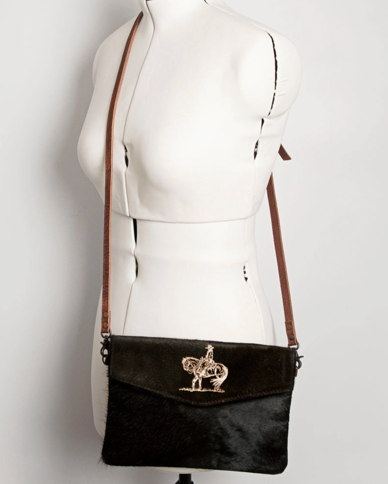 Black handbag with a decorative element on a mannequin against a white background