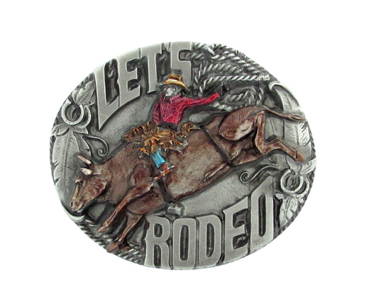 "Let's Rodeo" belt buckle with enamel inlays featuring a cowboy on a bucking bull bordered with feathers, horseshoes, and rope. Fits standard belts up to 2" wide. Made in USA.