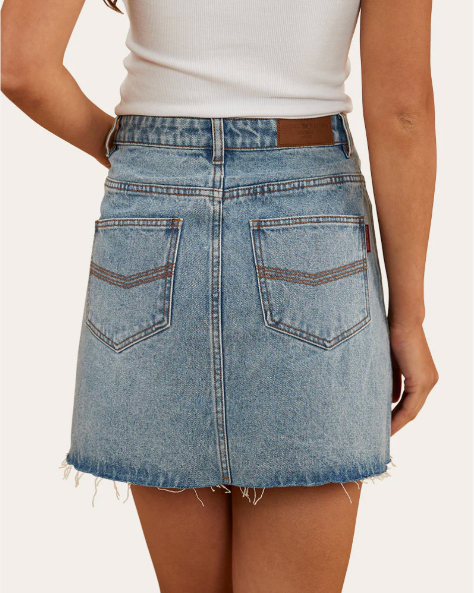 Denim skirt worn by a person on a plain background
